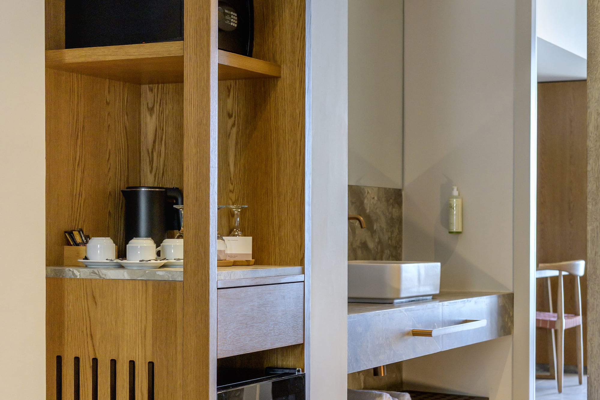 Hotel room: wooden cabinet, mini-fridge, coffee station, and bathroom vanity.