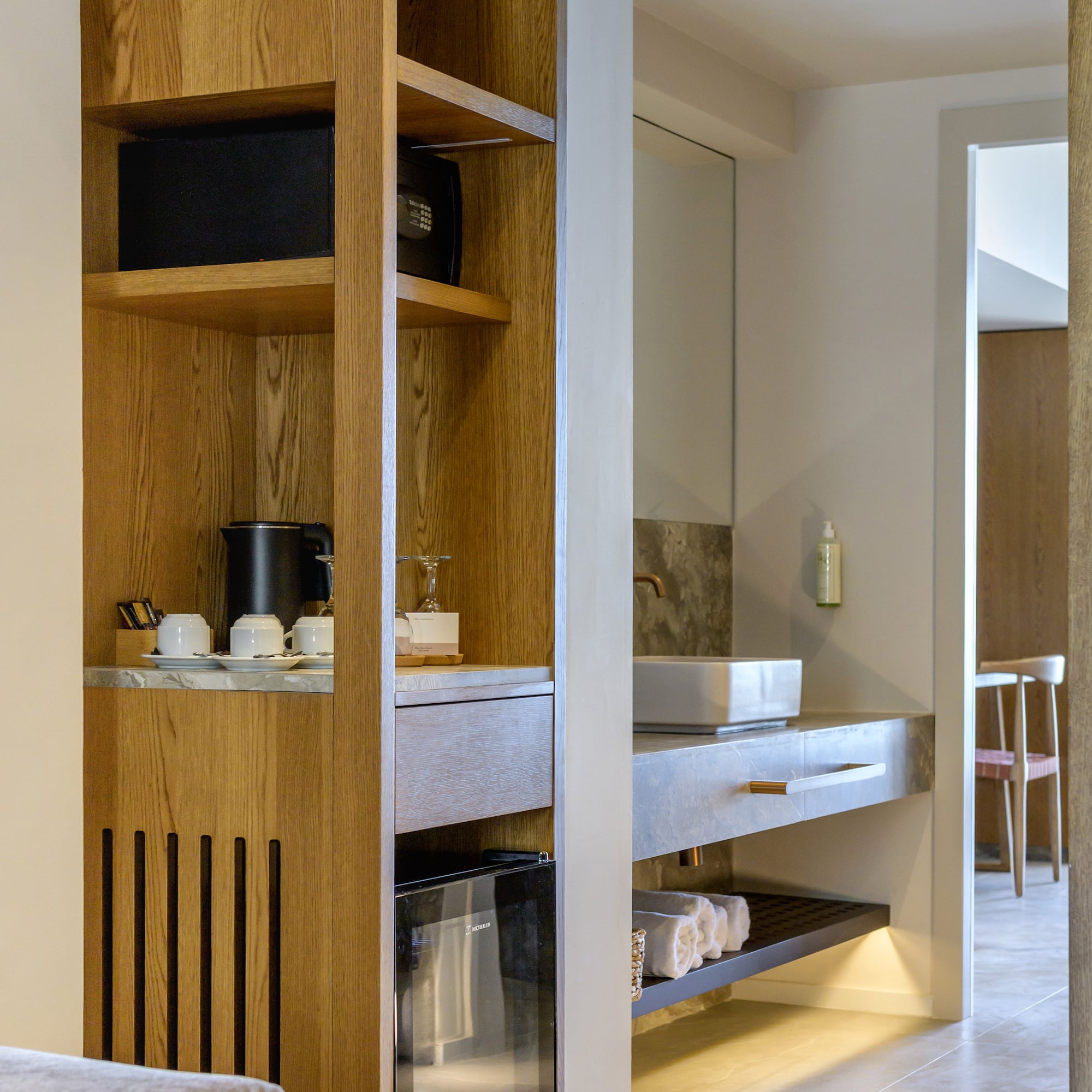 Hotel room: wooden cabinet, mini-fridge, coffee station, and bathroom vanity.