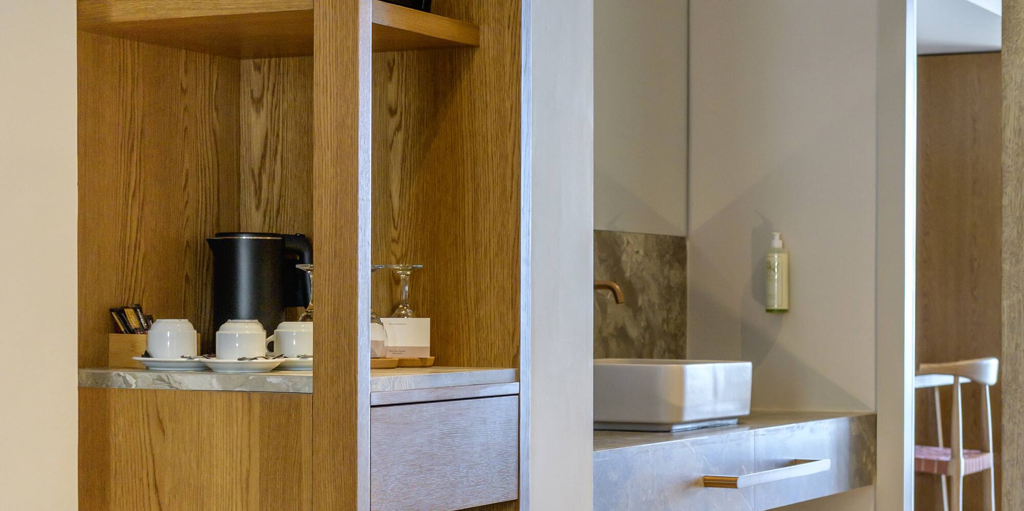 Hotel room: wooden cabinet, mini-fridge, coffee station, and bathroom vanity.