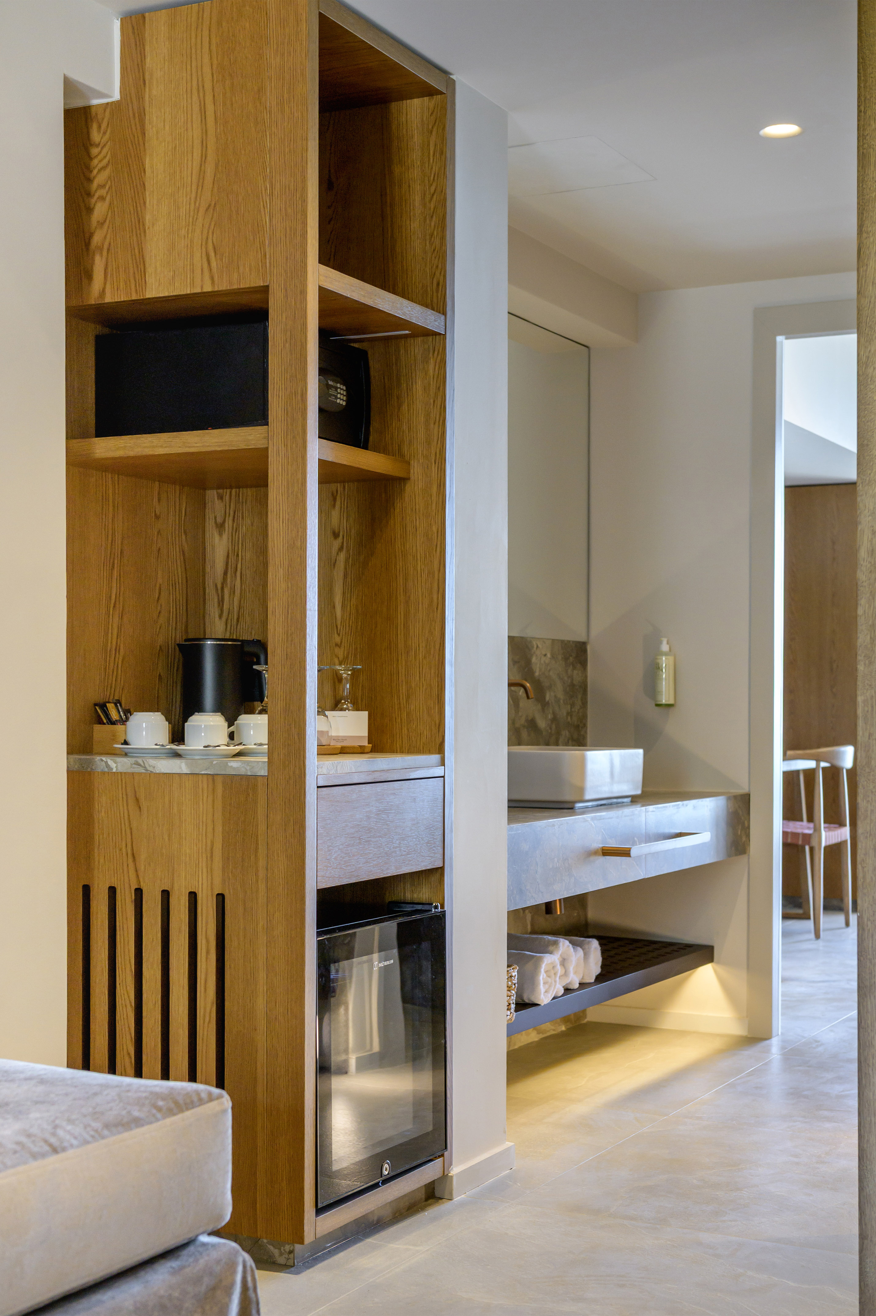 Hotel room: wooden cabinet, mini-fridge, coffee station, and bathroom vanity.