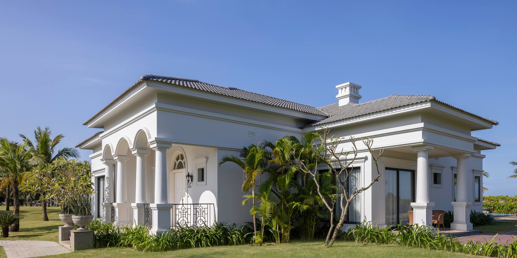 a white house with a lawn and trees