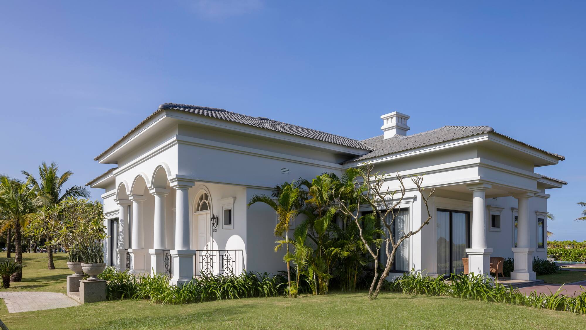 a white house with a lawn and trees