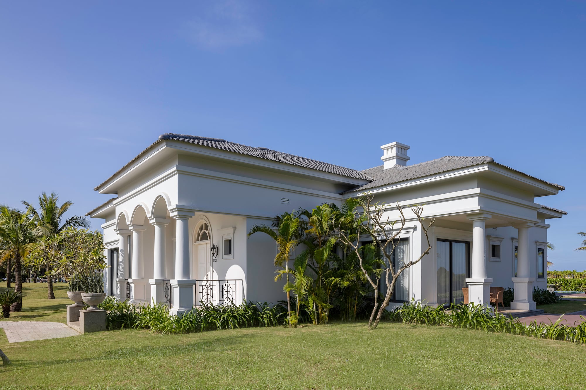 a white house with a lawn and trees
