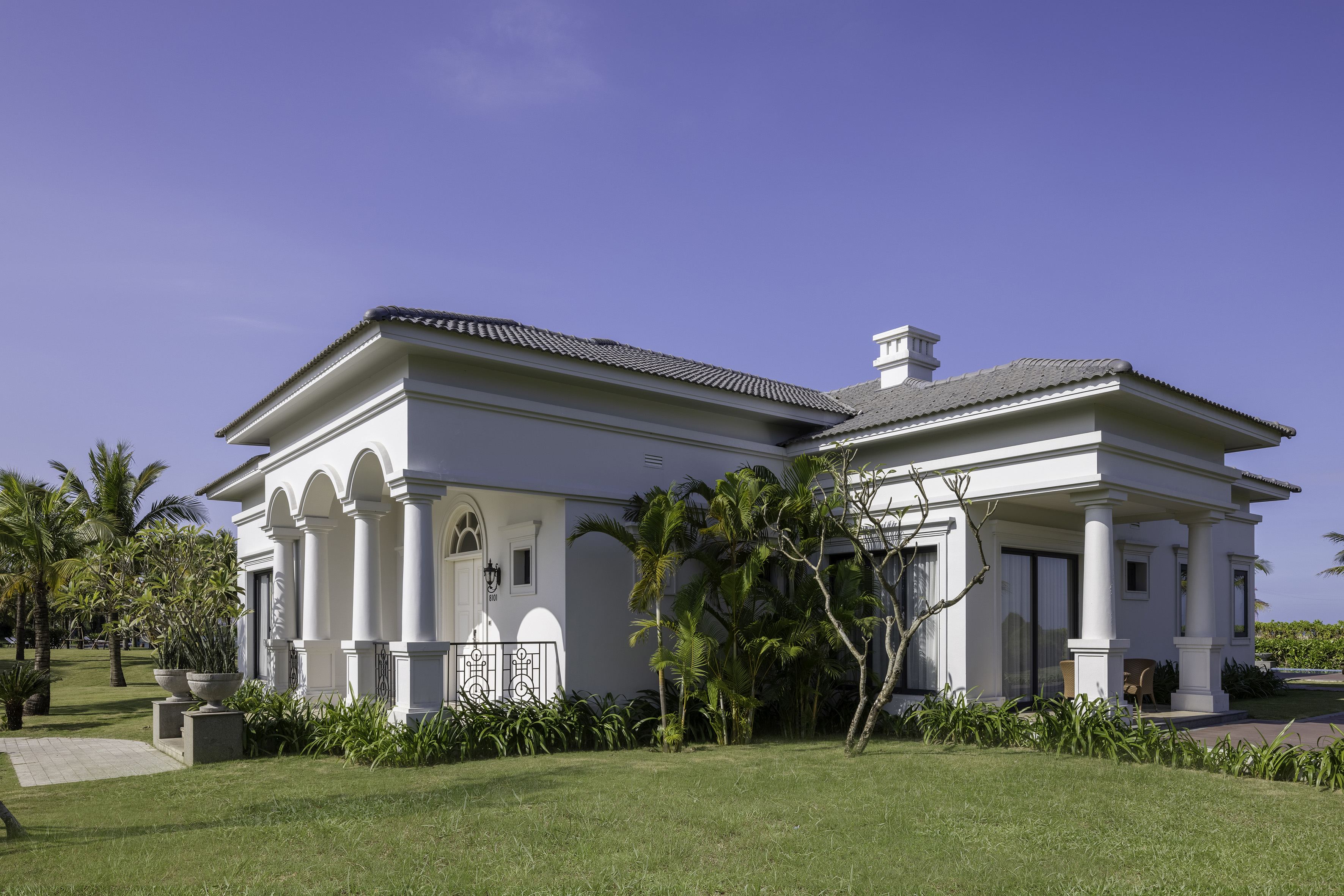 a white house with a lawn and trees