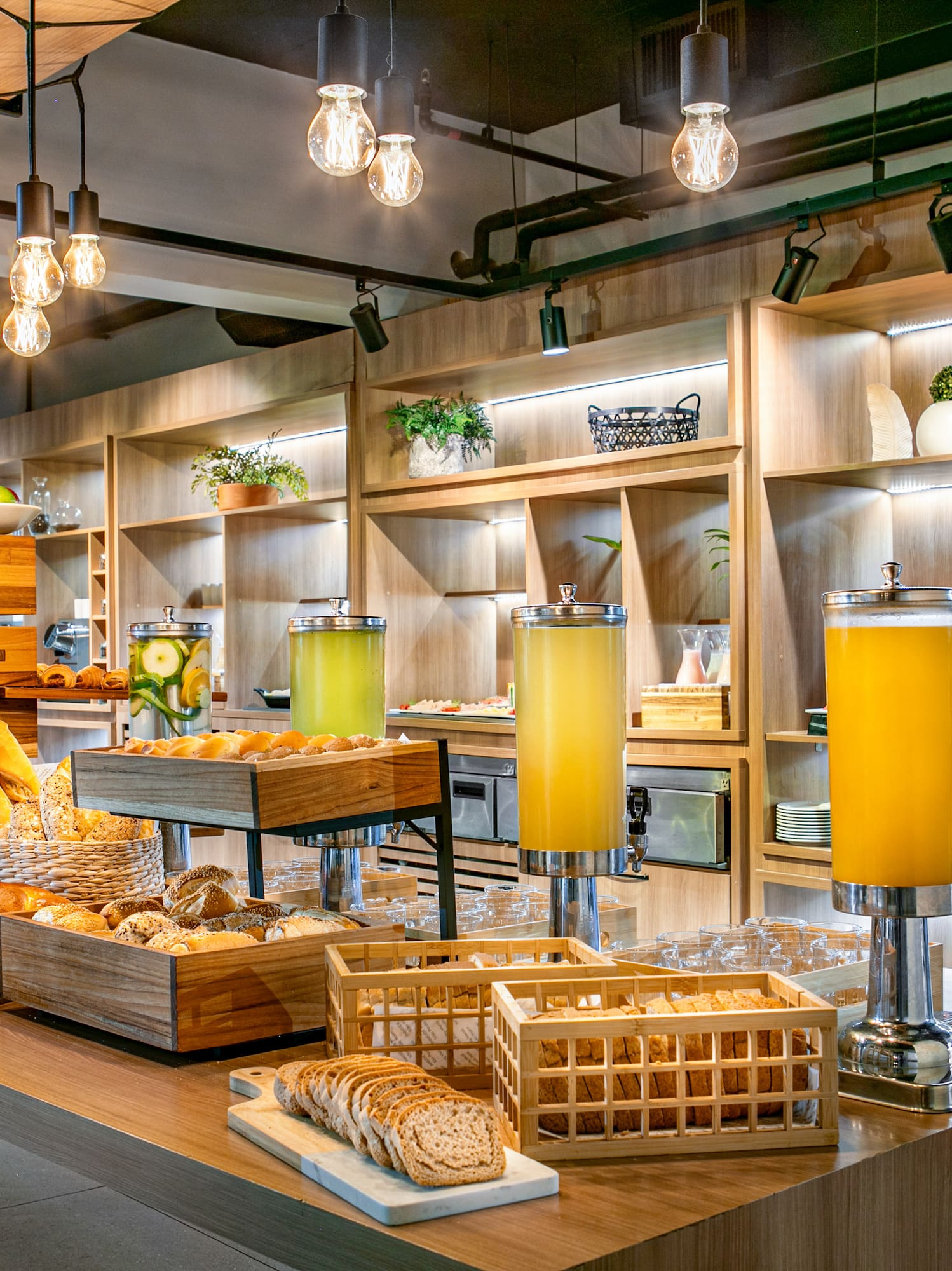 Hotel breakfast buffet with pastries, breads, juices, and modern wood decor.