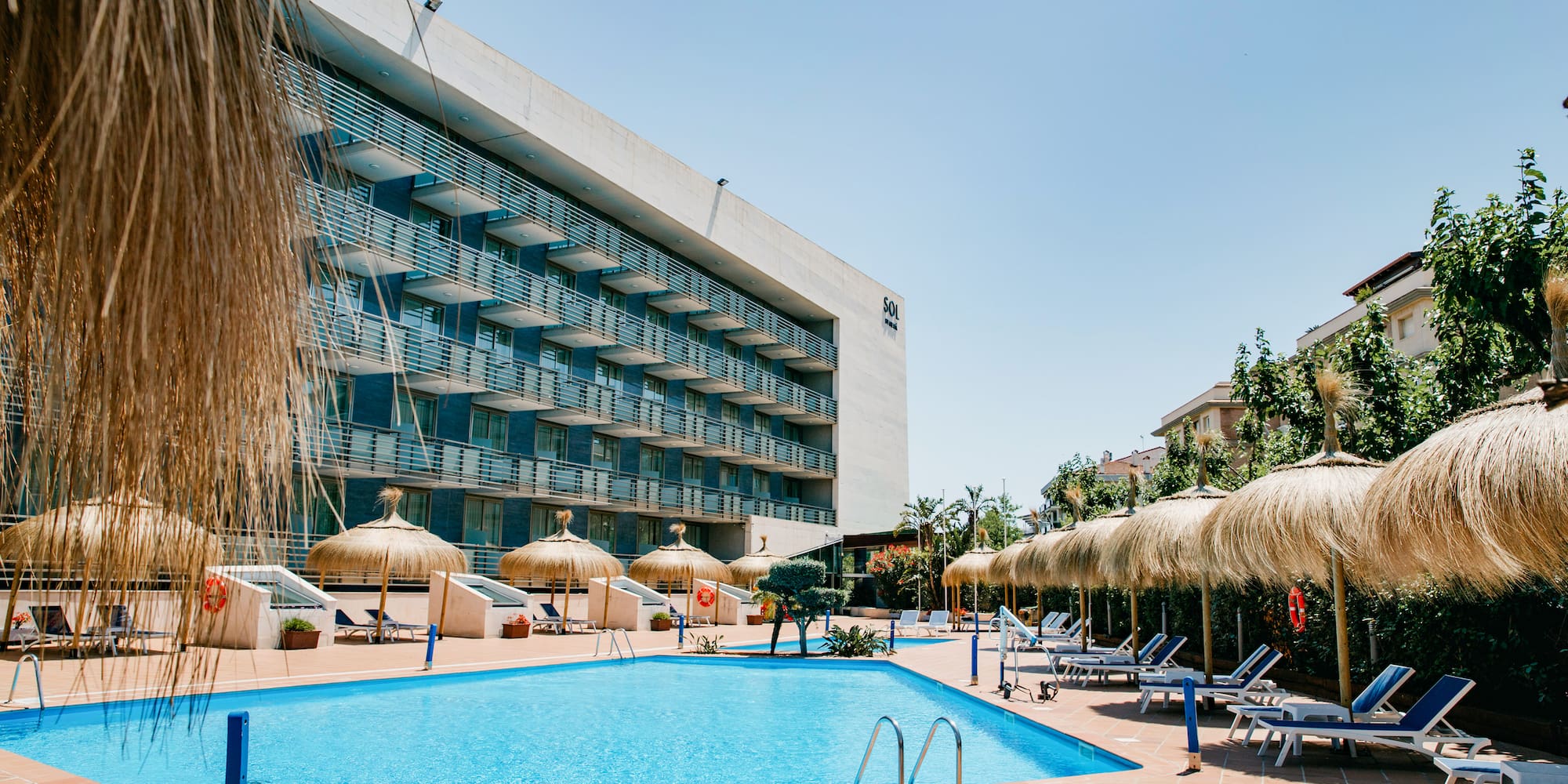 a pool with umbrellas and chairs in front of a building
