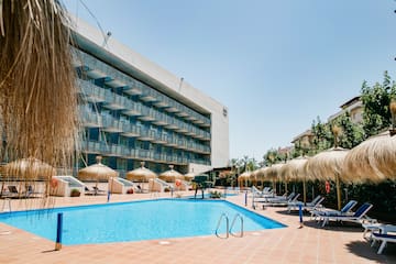 a pool with umbrellas and chairs in front of a building