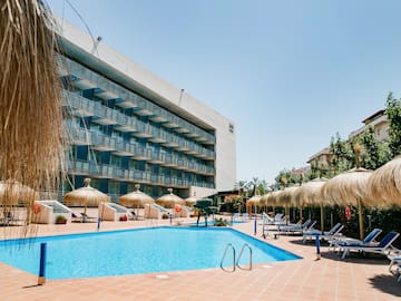 a pool with umbrellas and chairs in front of a building