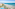 Aerial view of resort pool, palm trees, sandy beach, and blue ocean.