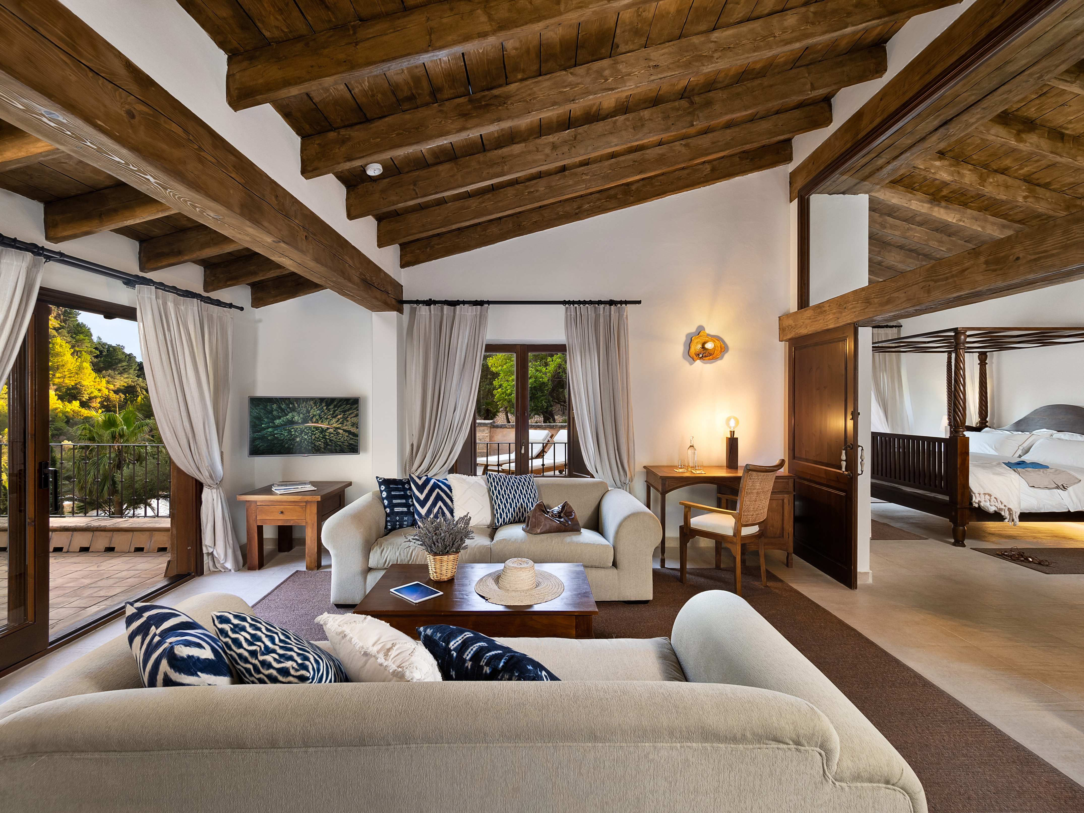 Mediterranean living room with exposed wood beams, cozy sofas, and garden view.