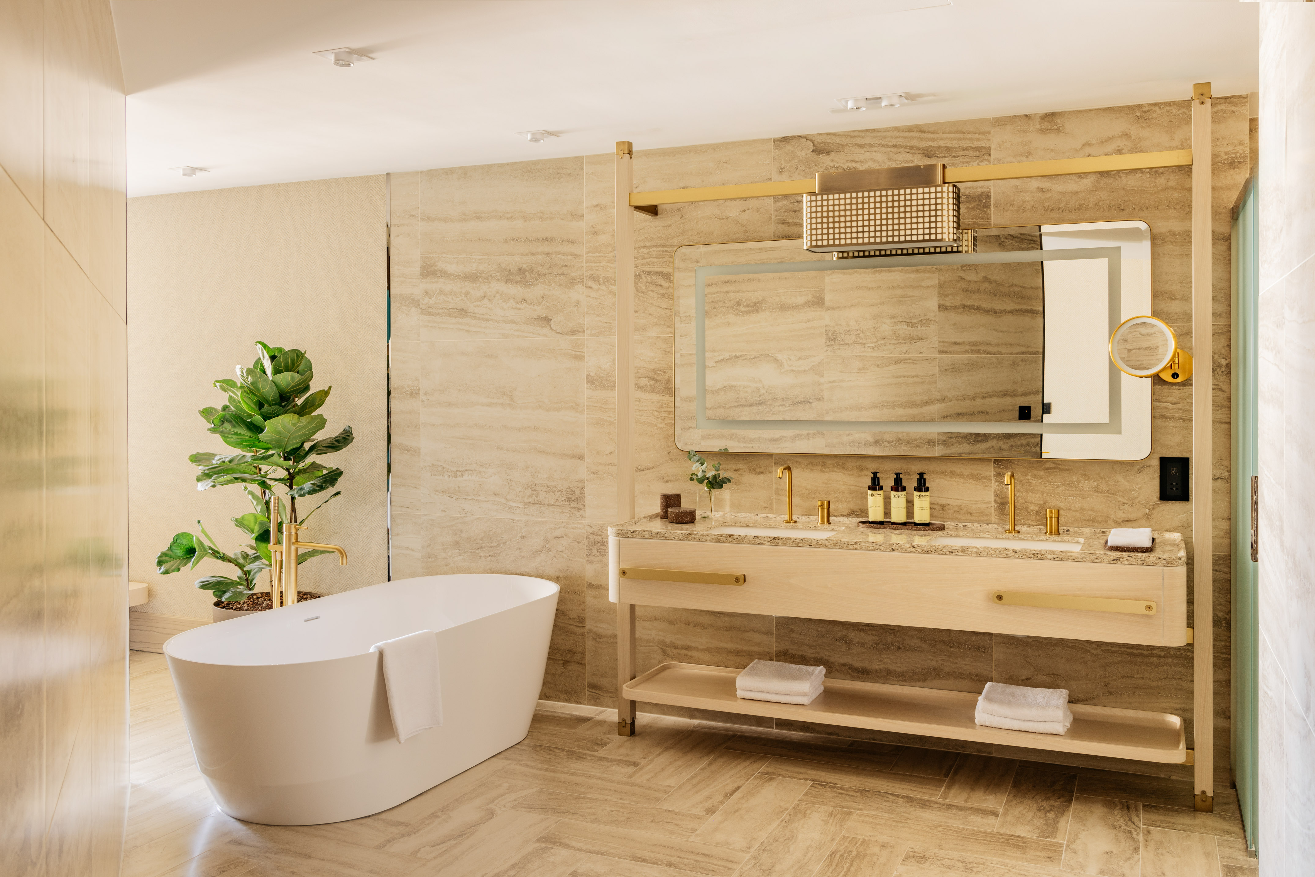 Luxury bathroom with white freestanding tub, double vanity, and gold accents.
