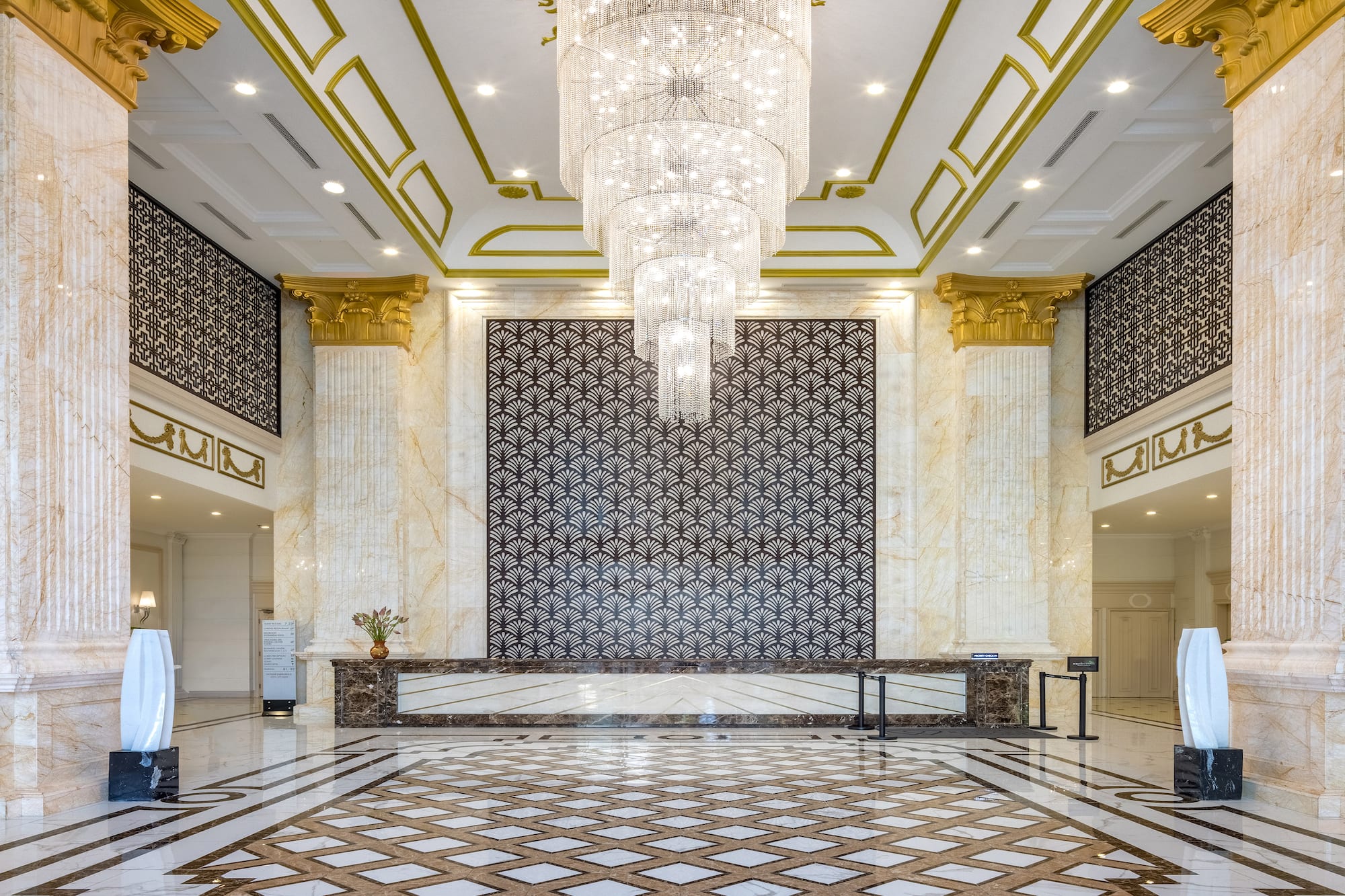 Luxury hotel reception with sparkling chandelier, marble and gold decor.