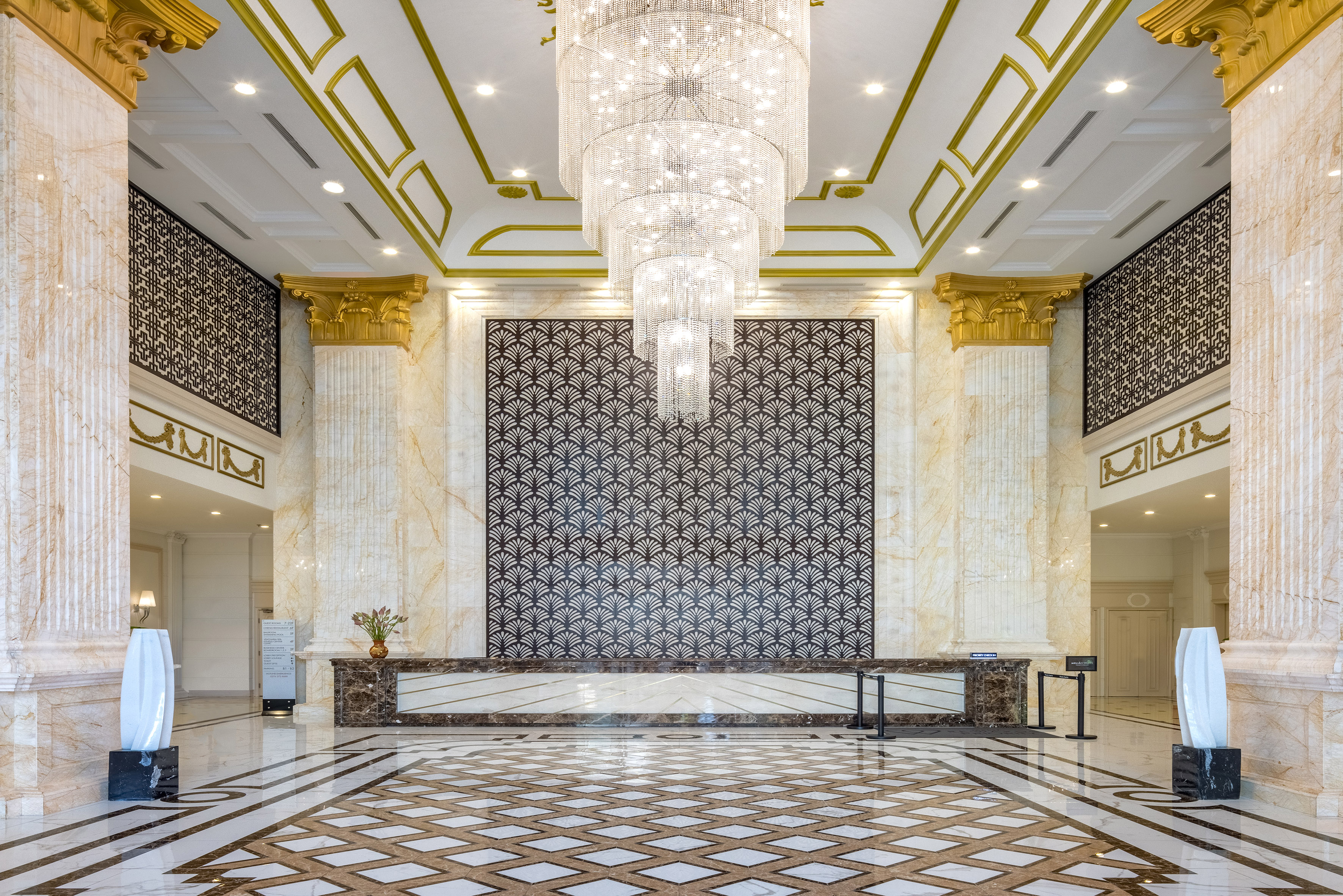 Luxury hotel reception with sparkling chandelier, marble and gold decor.