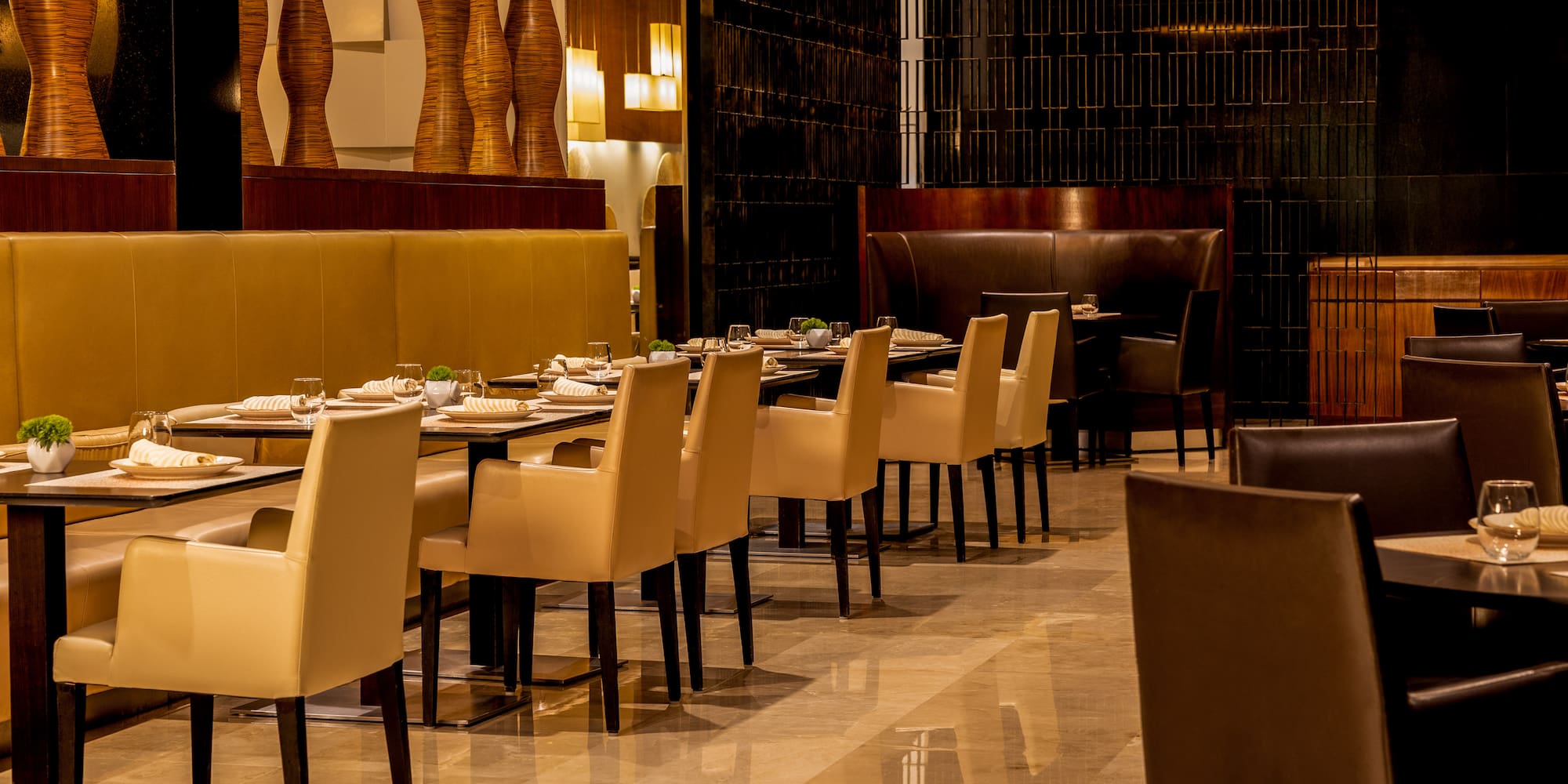 Luxury restaurant interior with set dining tables and elegant cream chairs.