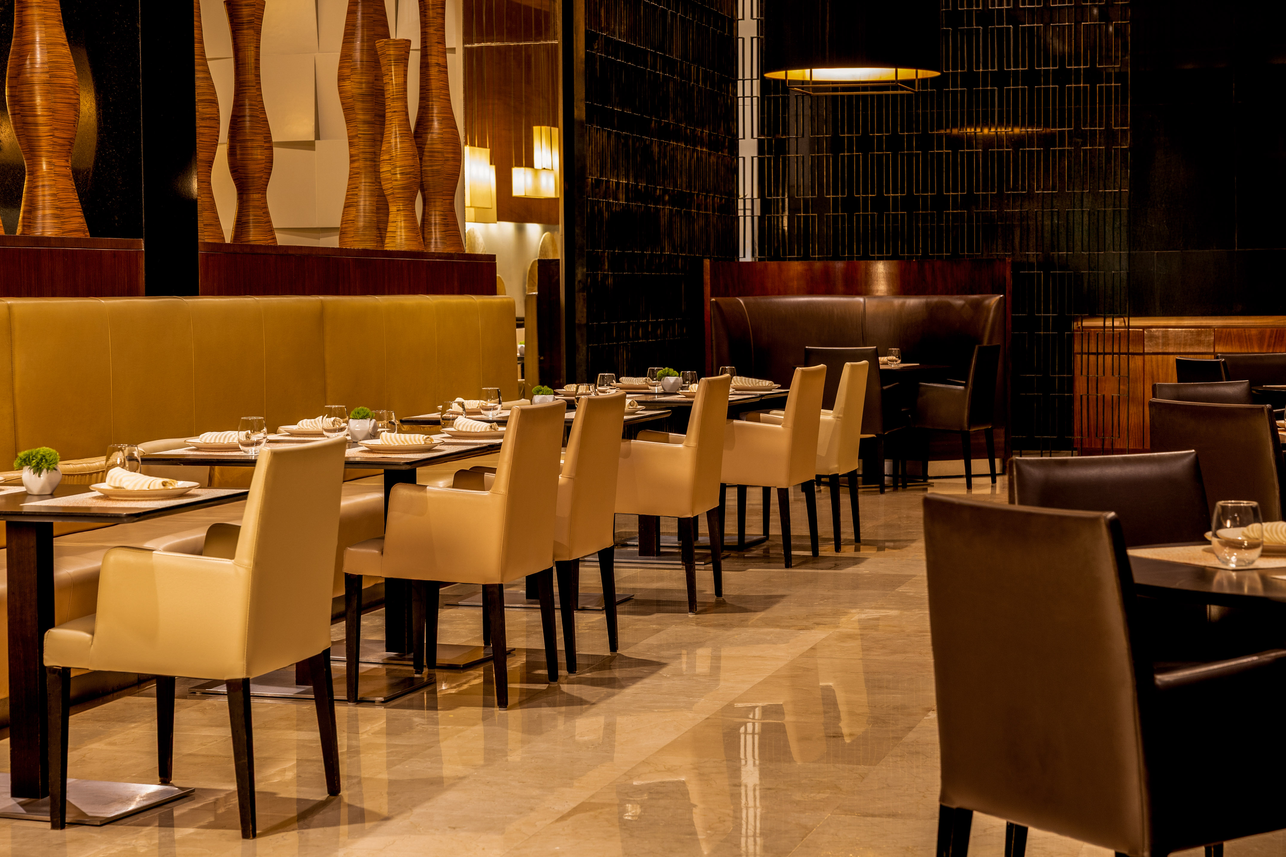 Luxury restaurant interior with set dining tables and elegant cream chairs.
