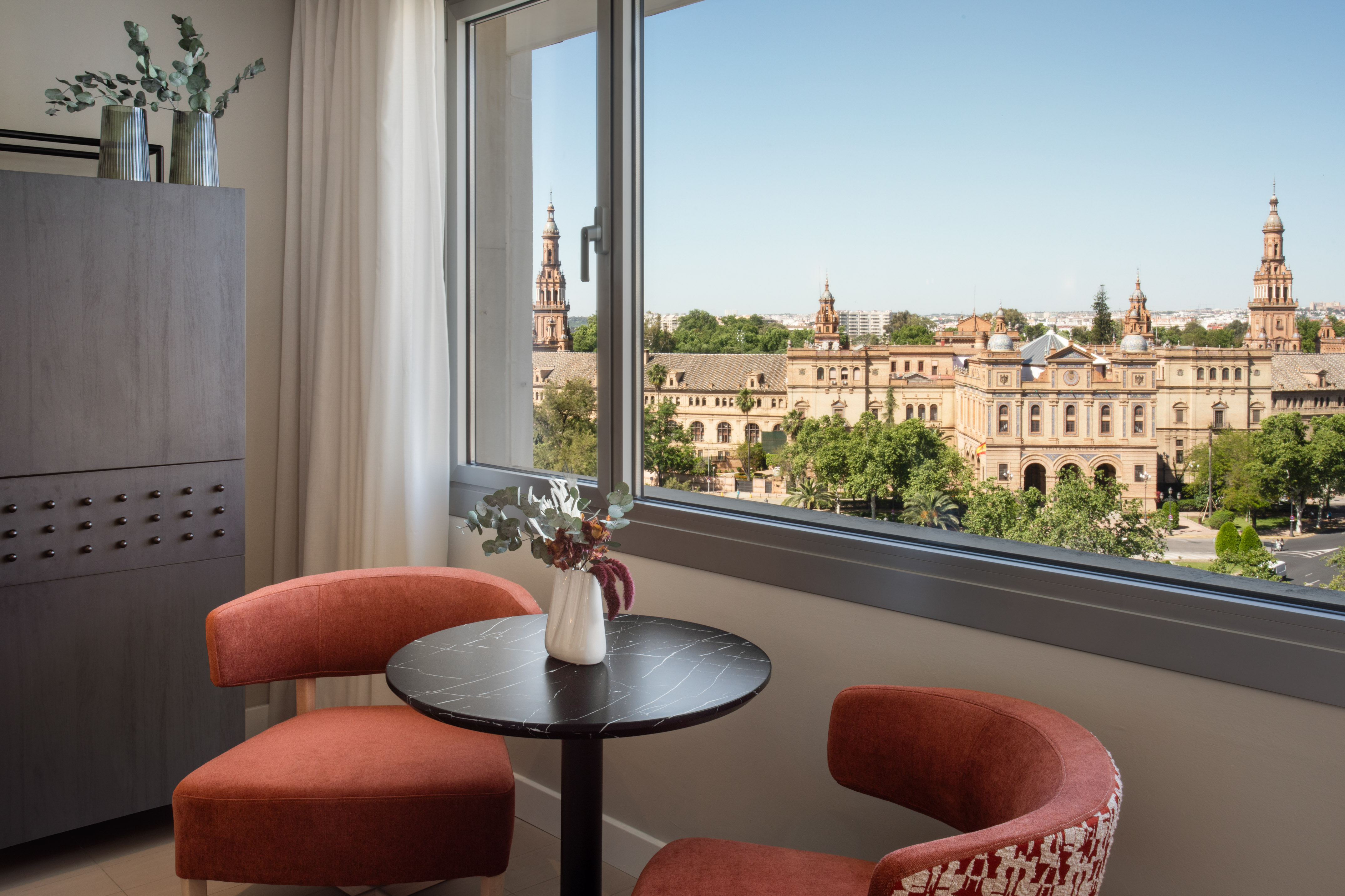 Hotel room with panoramic window view of Seville's Plaza de España.