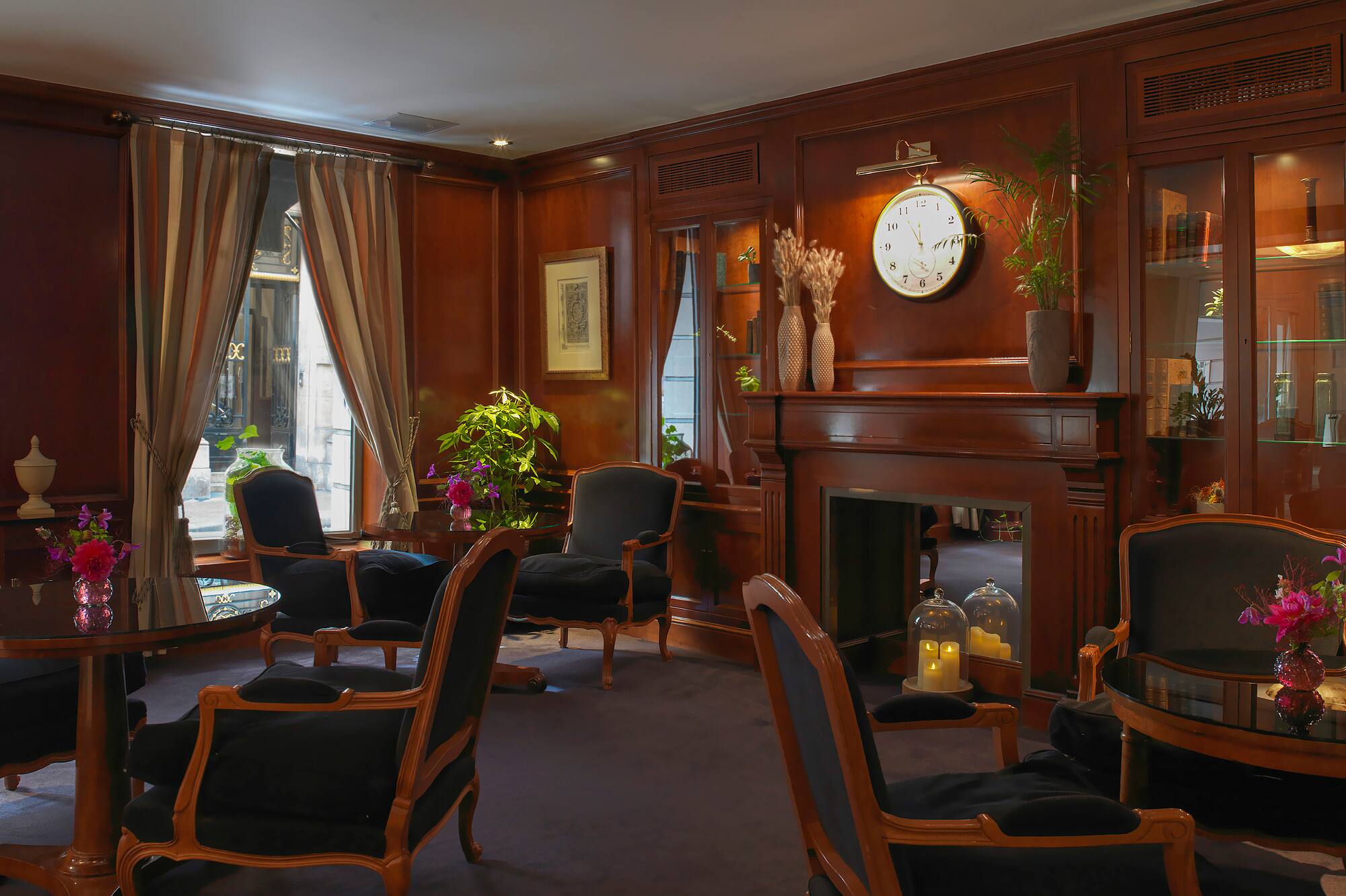 Elegant hotel lounge with dark wood paneling, black armchairs, and fireplace.