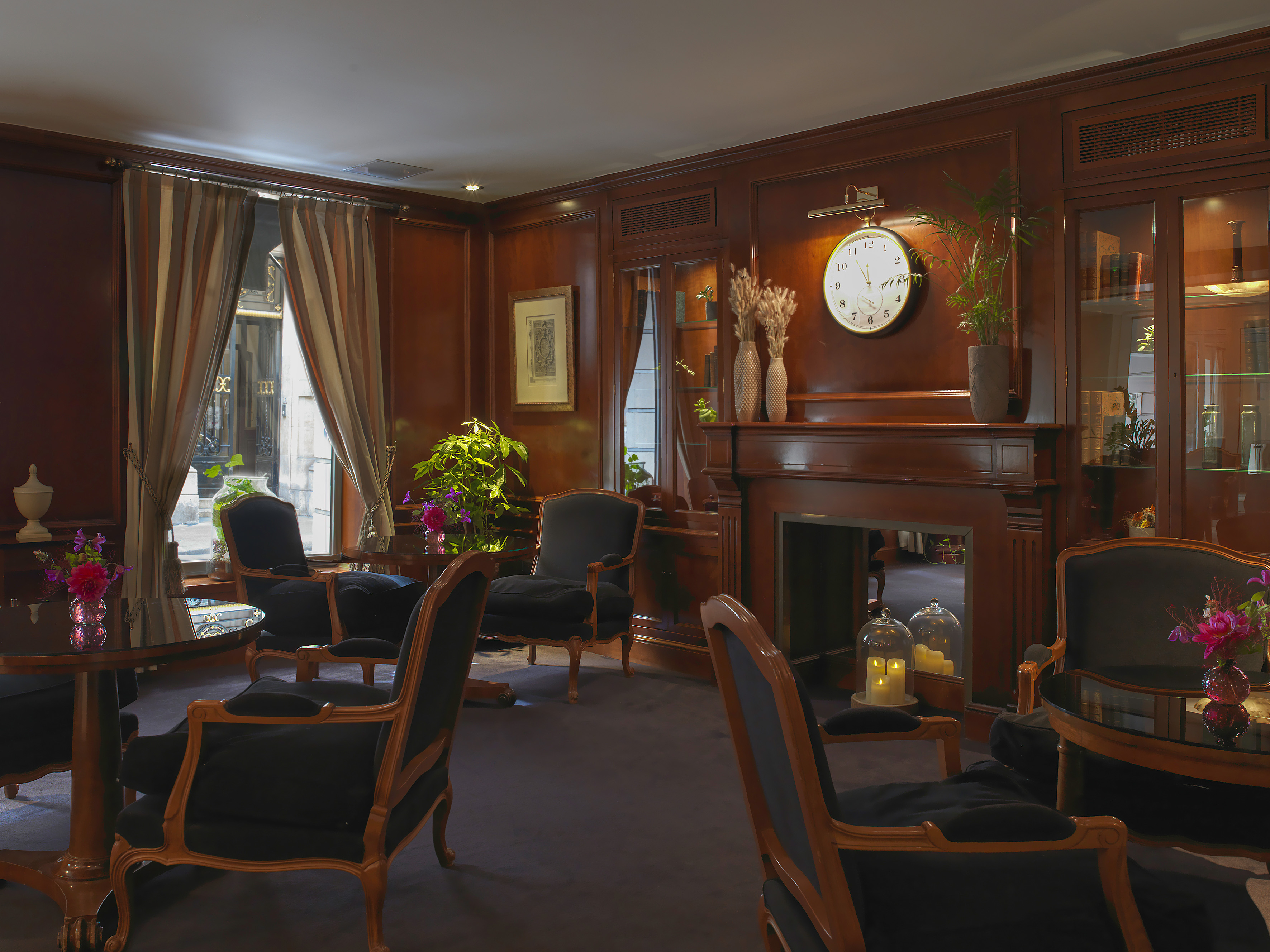 Elegant hotel lounge with dark wood paneling, black armchairs, and fireplace.