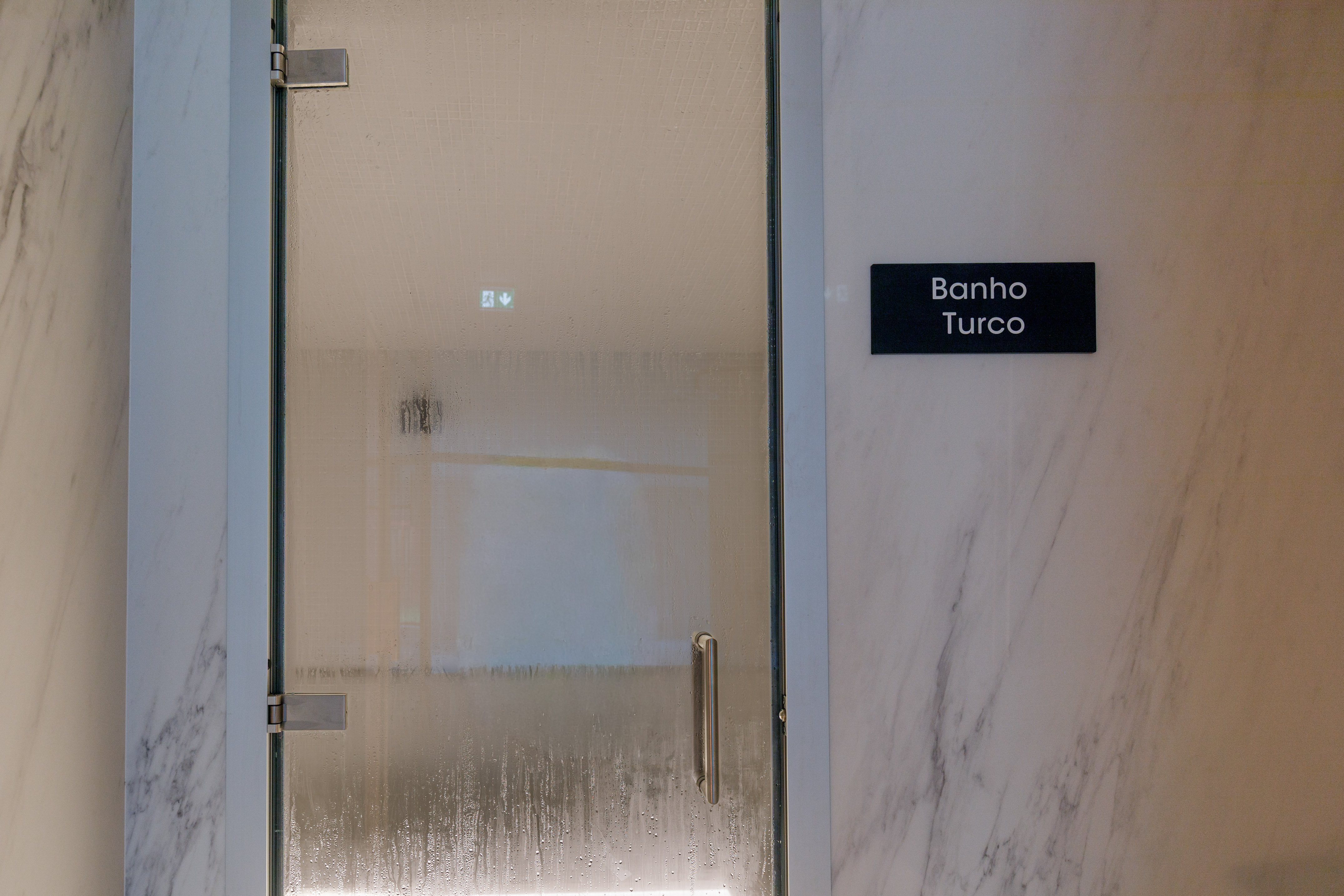 Condensed glass door of a Banho Turco (Turkish Bath) with marble walls.