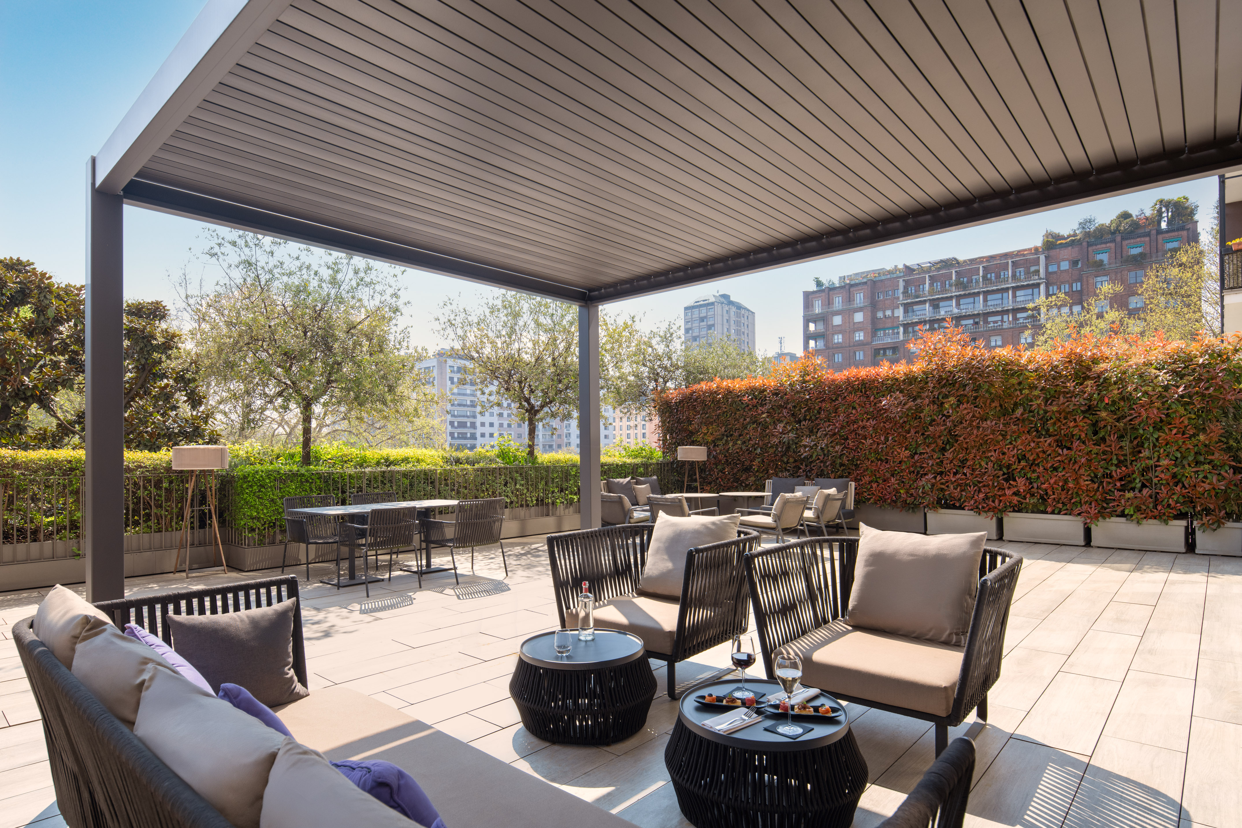 Modern outdoor patio with pergola, stylish lounge seating, and city views.