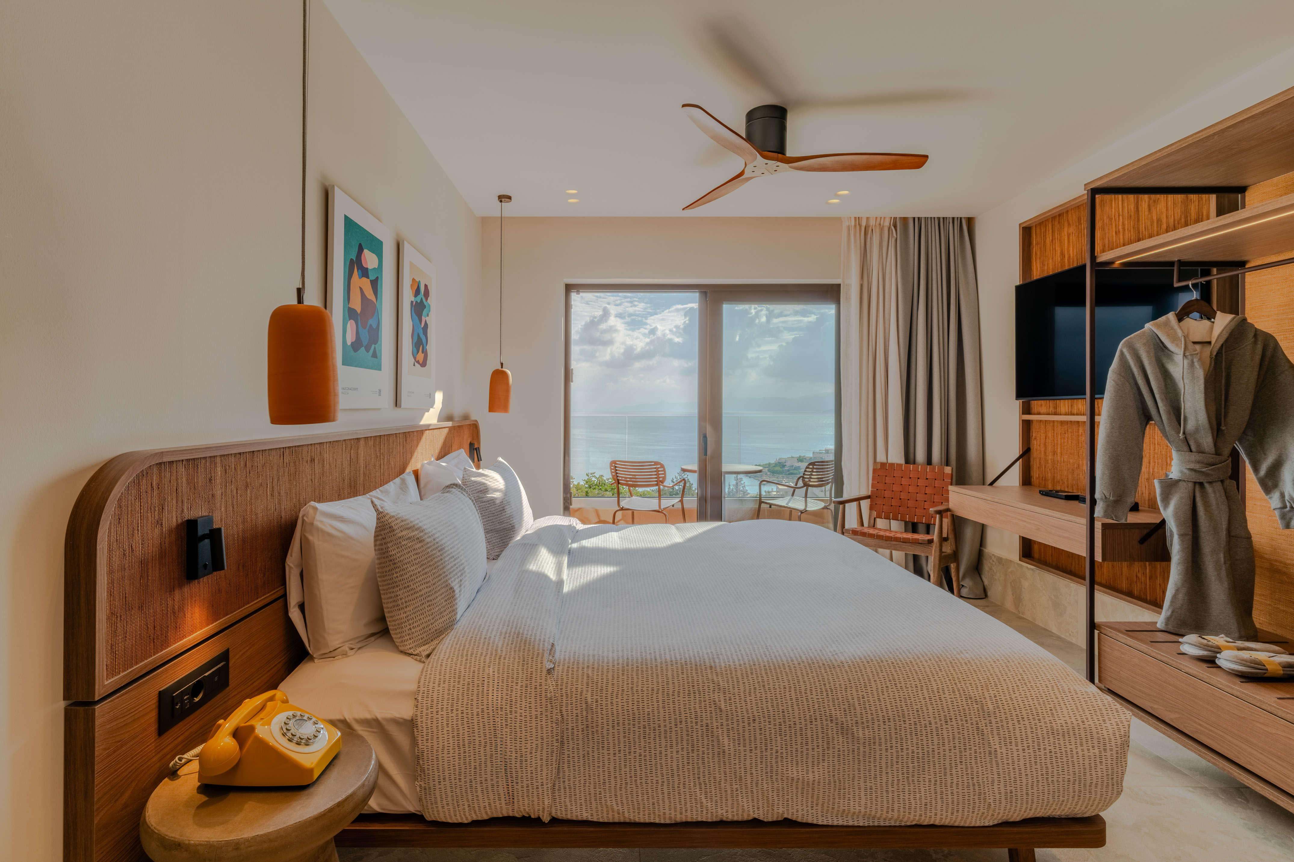 Modern hotel room with sea view balcony, king bed, and contemporary design.