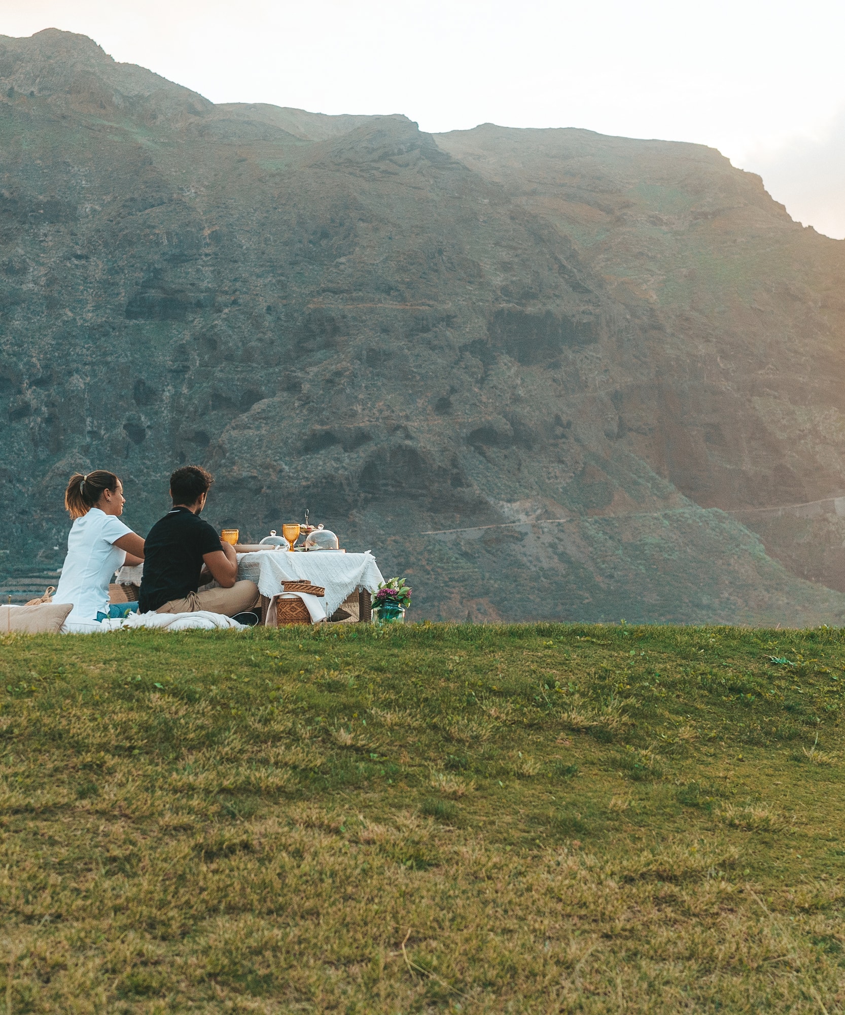a couple sitting on a blanket on a hill