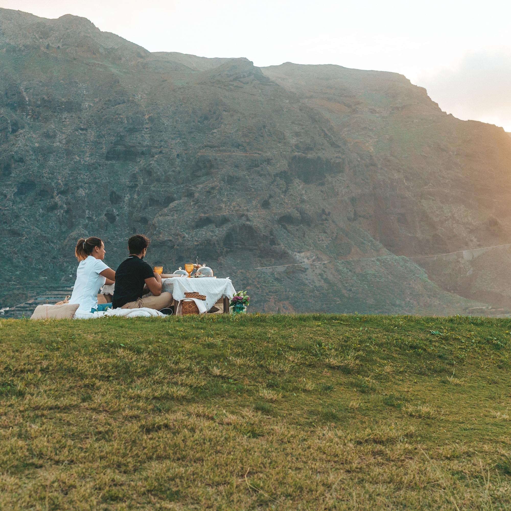 a couple sitting on a blanket on a hill