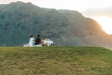 a couple sitting on a blanket on a hill