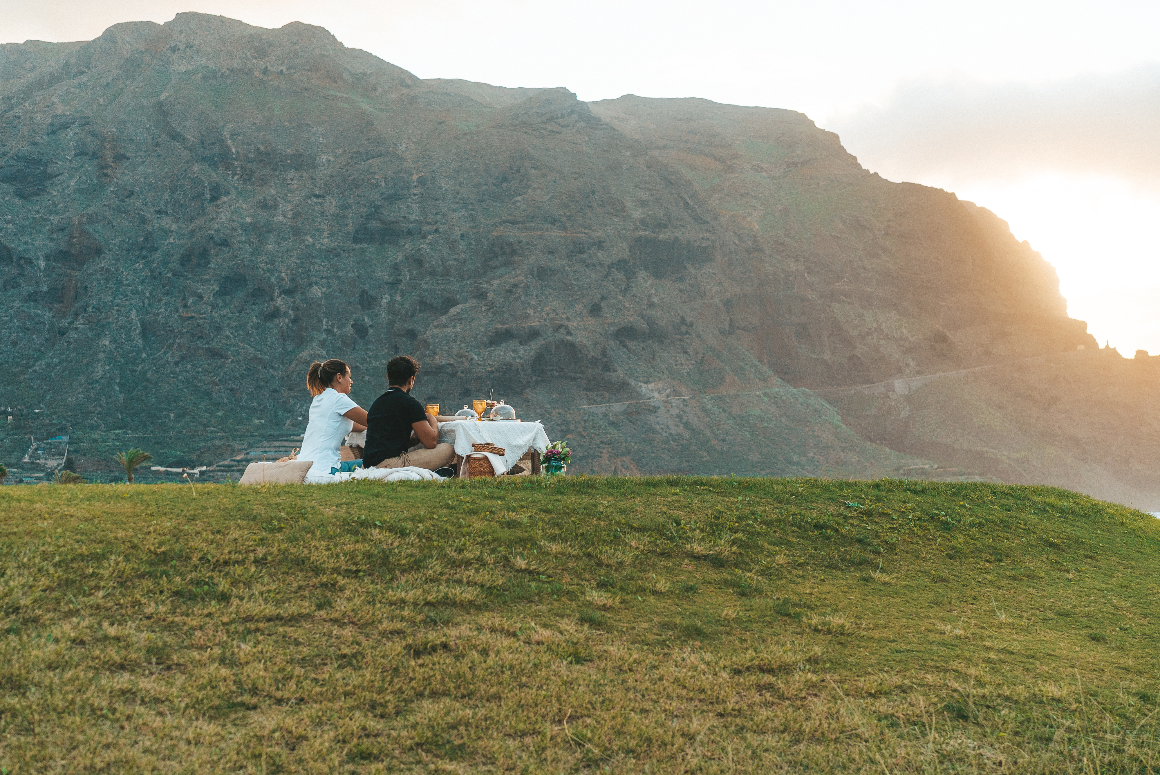 a couple sitting on a blanket on a hill