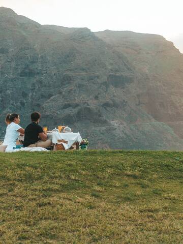 a couple sitting on a blanket on a hill