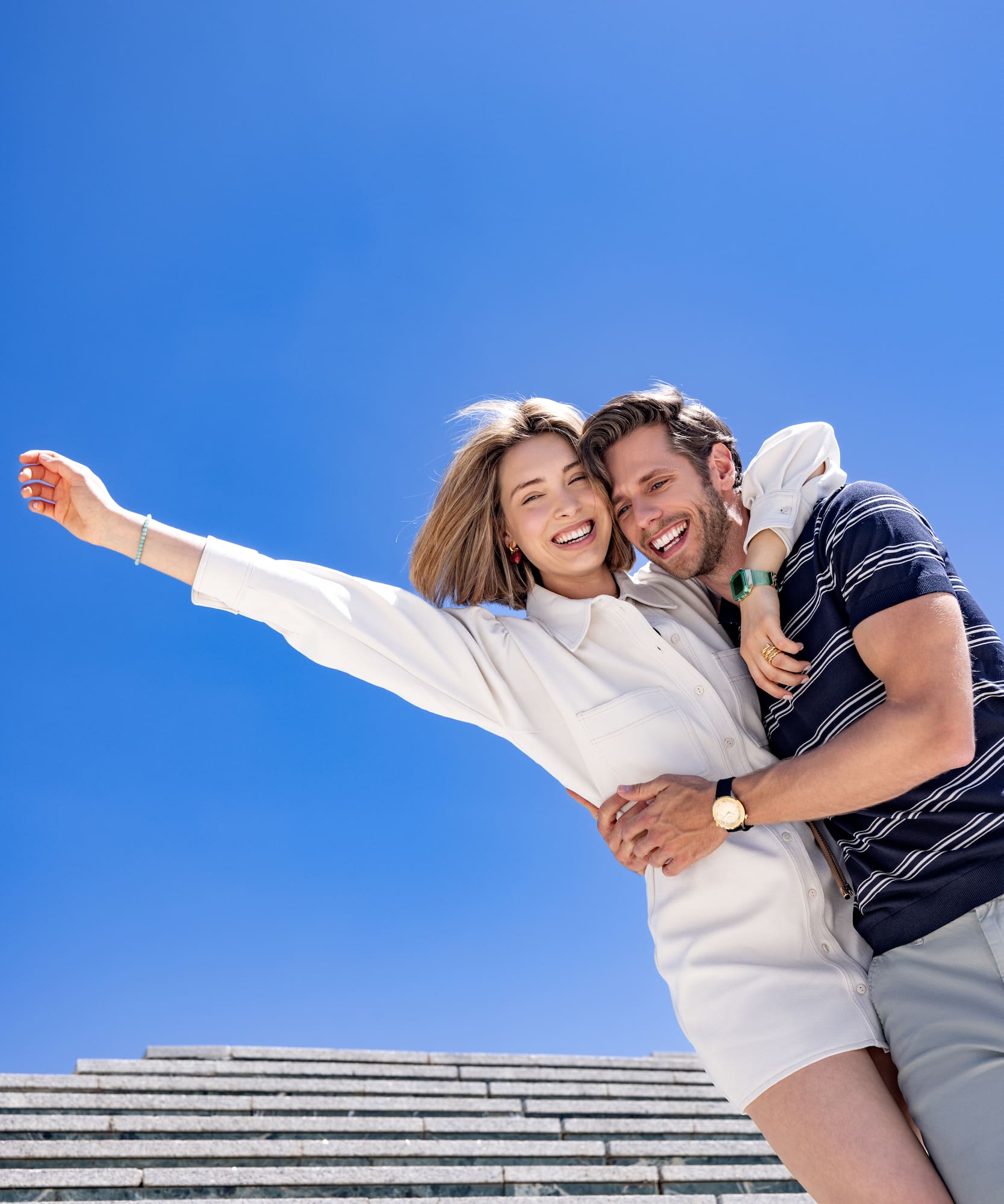 Joyful couple embracing and smiling outdoors under a blue sky.