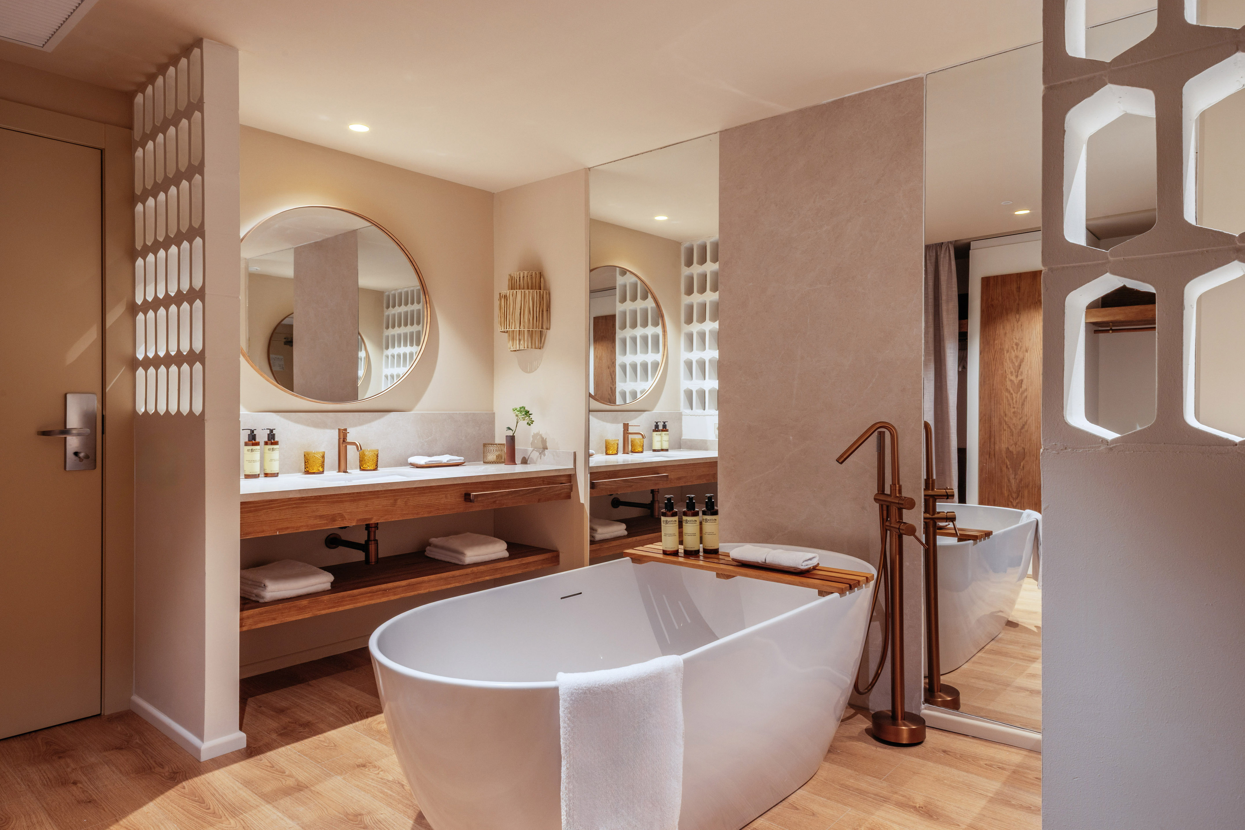 Modern bathroom with freestanding tub, double vanity, and warm wood accents.