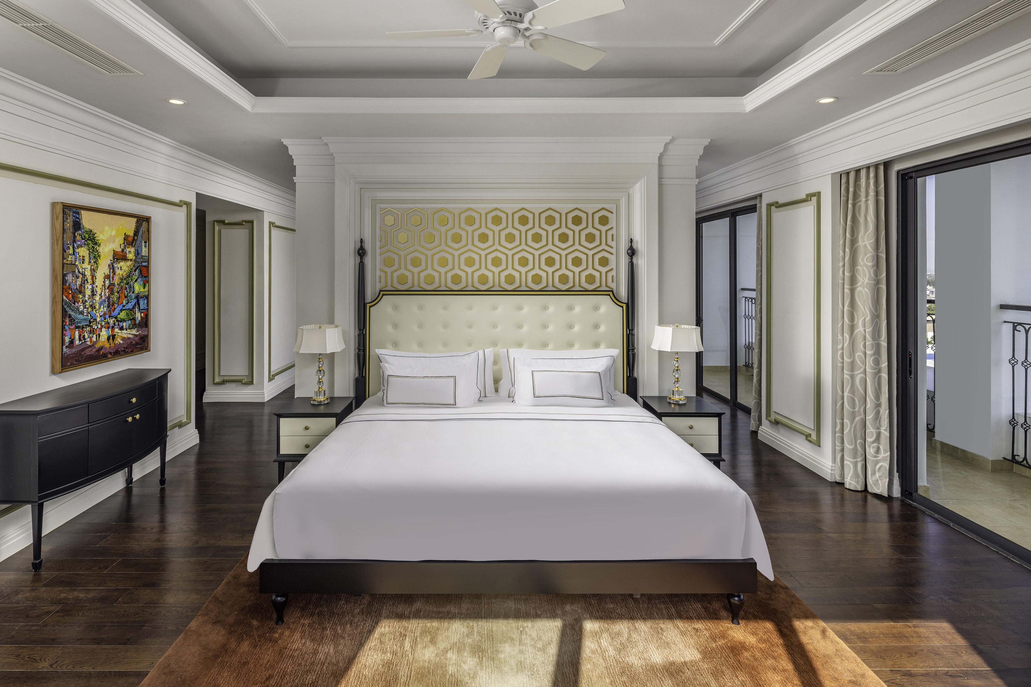 Elegant bedroom with king bed, gold accent wall, dark wood floor, and balcony.