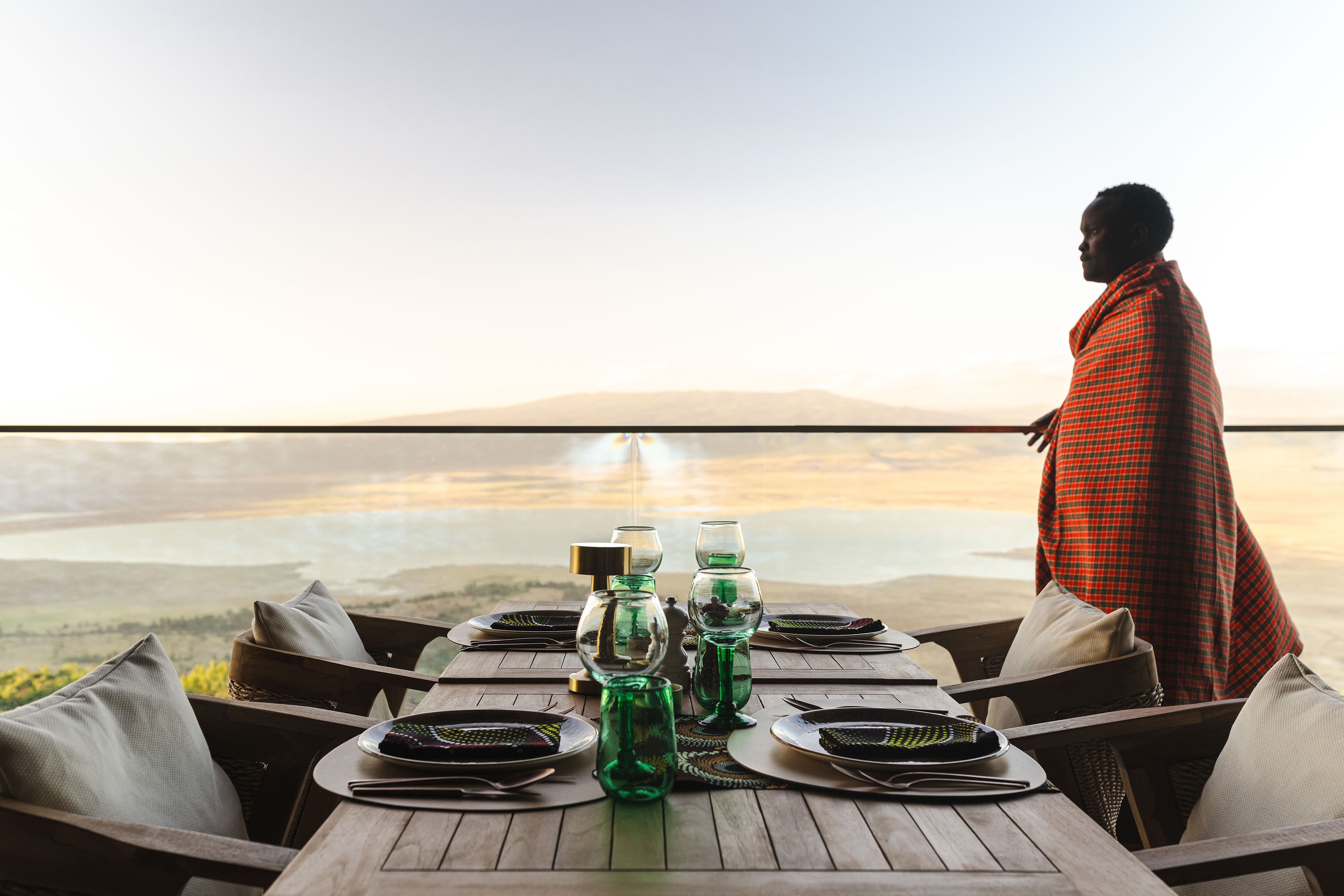 Maasai person views Ngorongoro Crater from safari lodge outdoor dining.