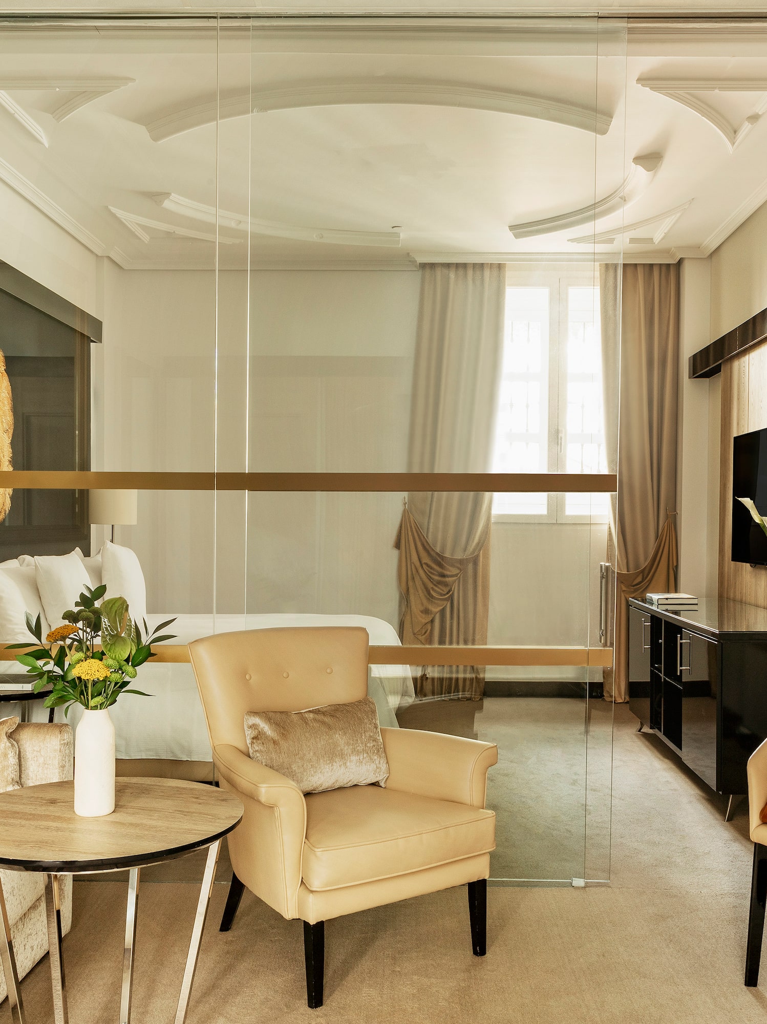 a room with a glass wall and a bed and chairs