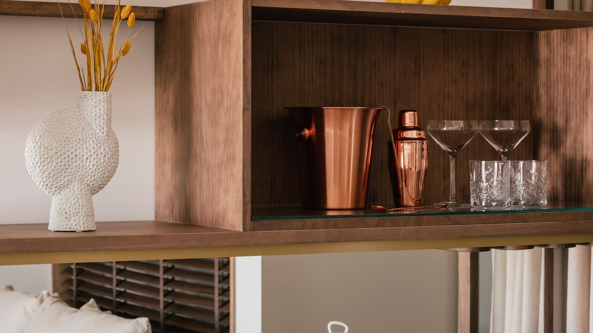 a shelf with a glass top and a vase of flowers on it