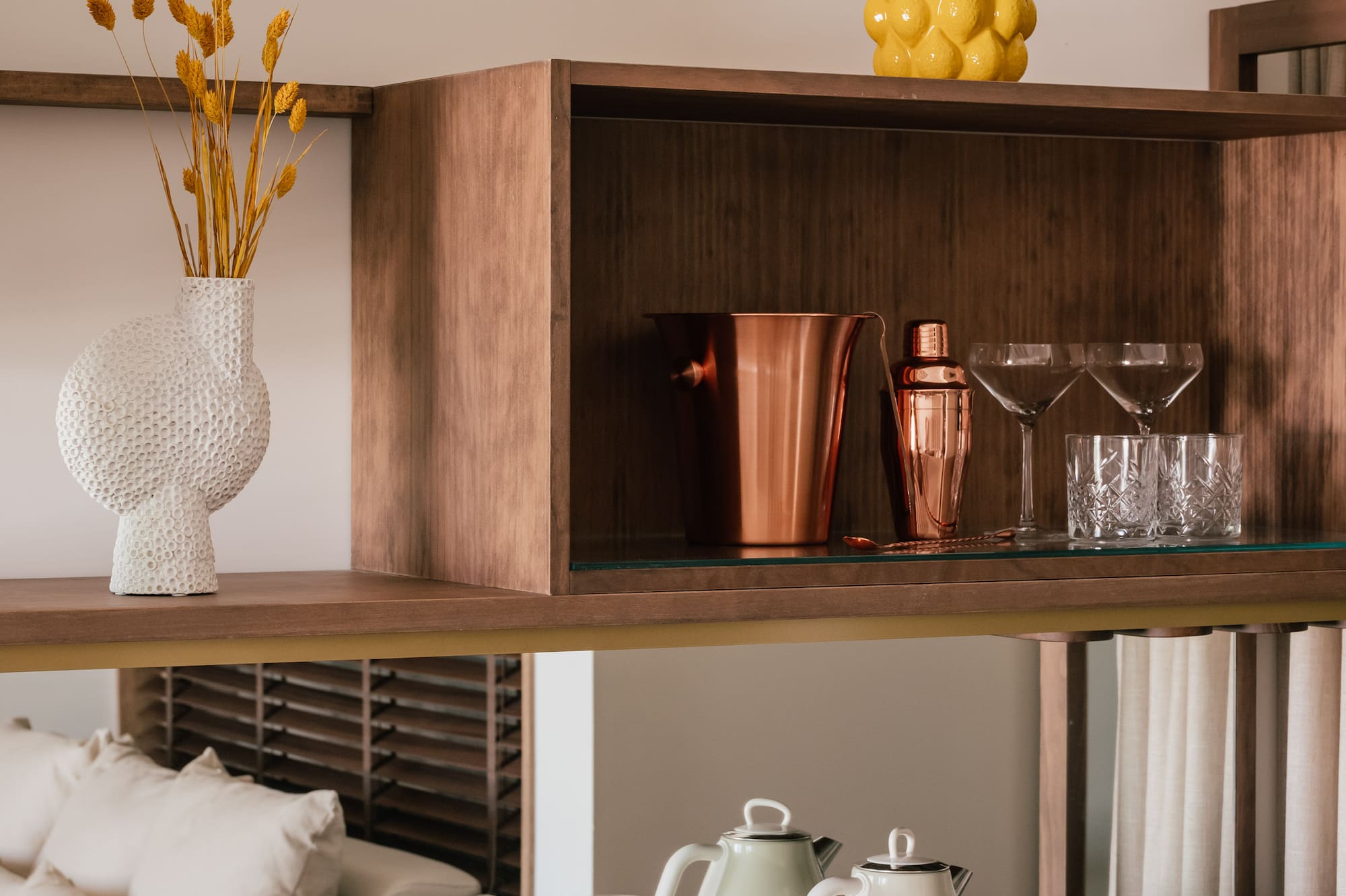 a shelf with a glass top and a vase of flowers on it