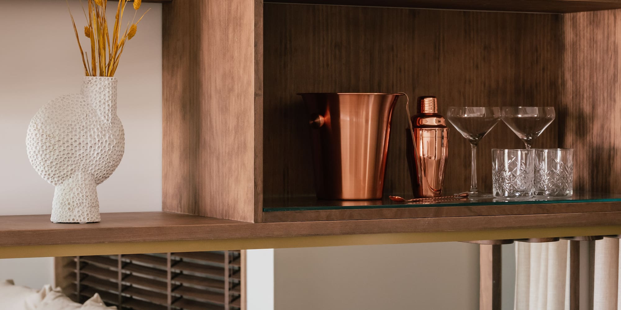 a shelf with a glass top and a vase of flowers on it