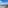Balcony view: clear blue sea, sandy beach, distant coastal city skyline.