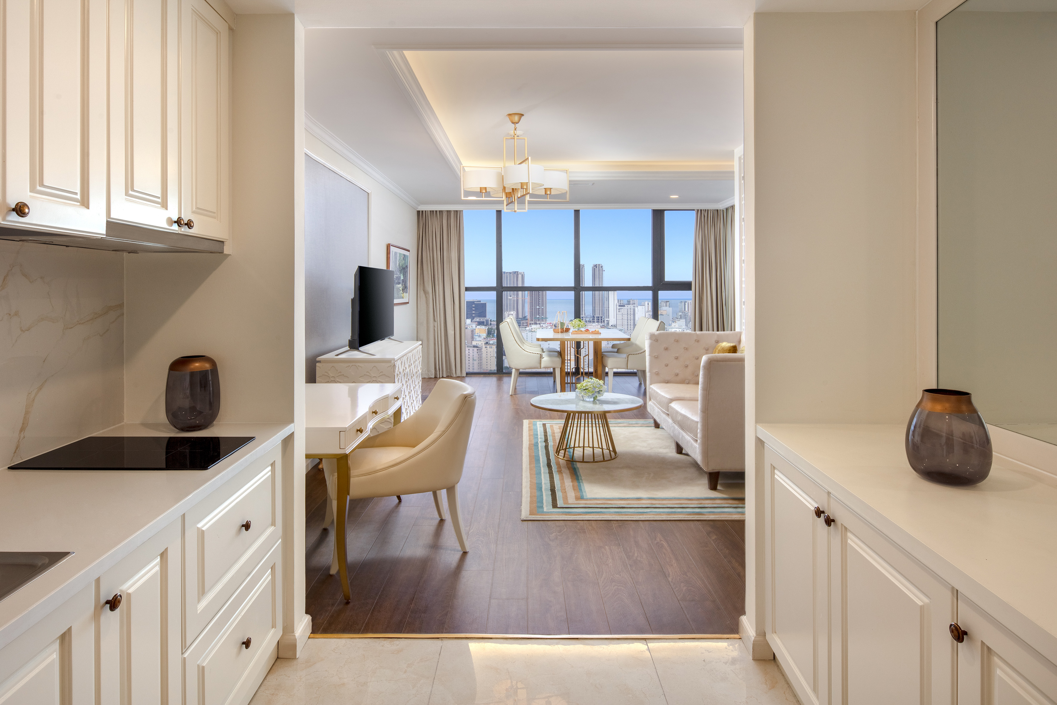 Modern hotel suite: kitchen, living, dining, work desk, city and ocean view.