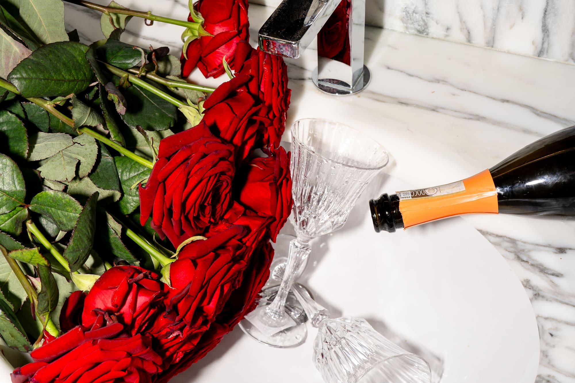 a bottle of champagne being poured into a sink with roses