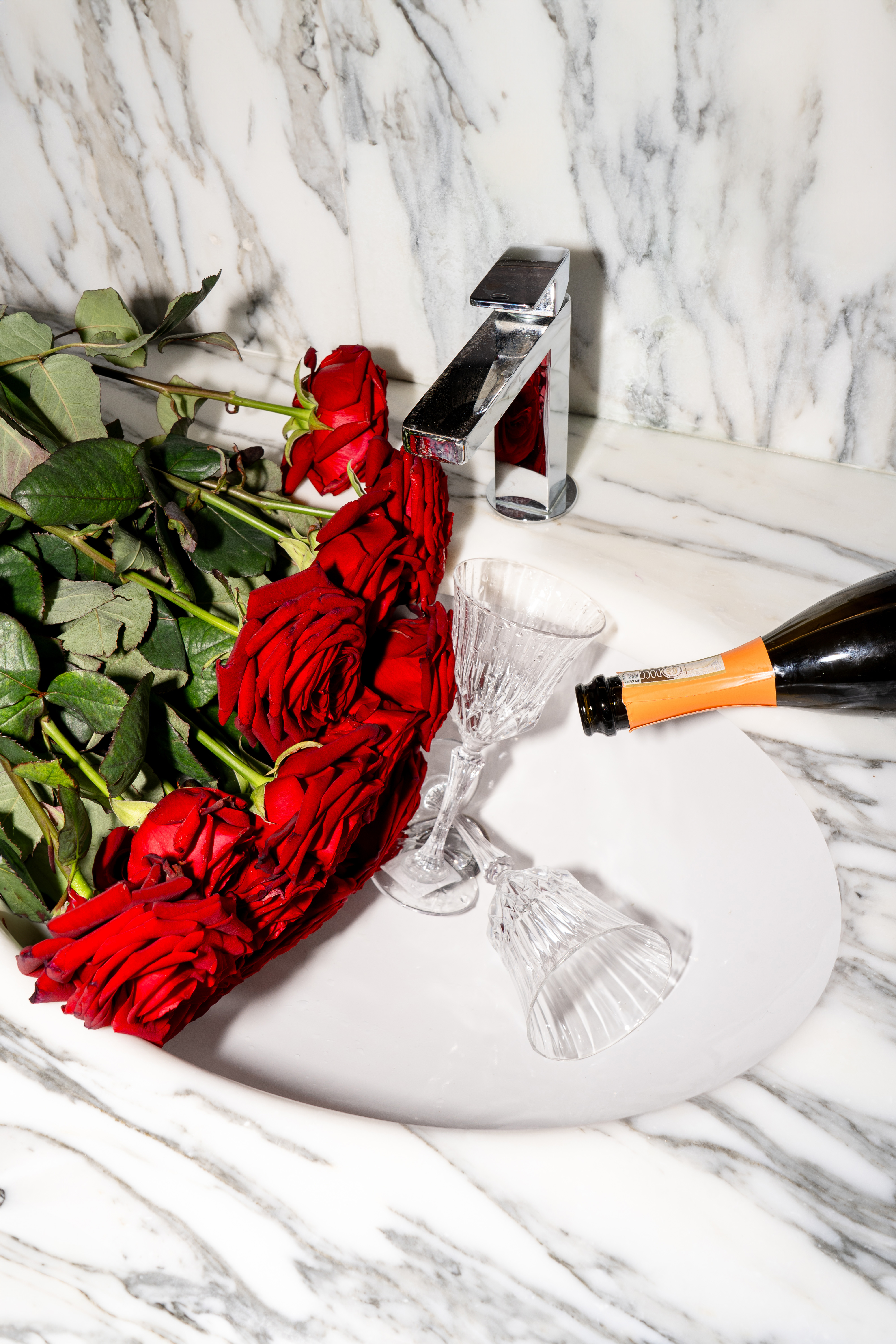 a bottle of champagne being poured into a sink with roses