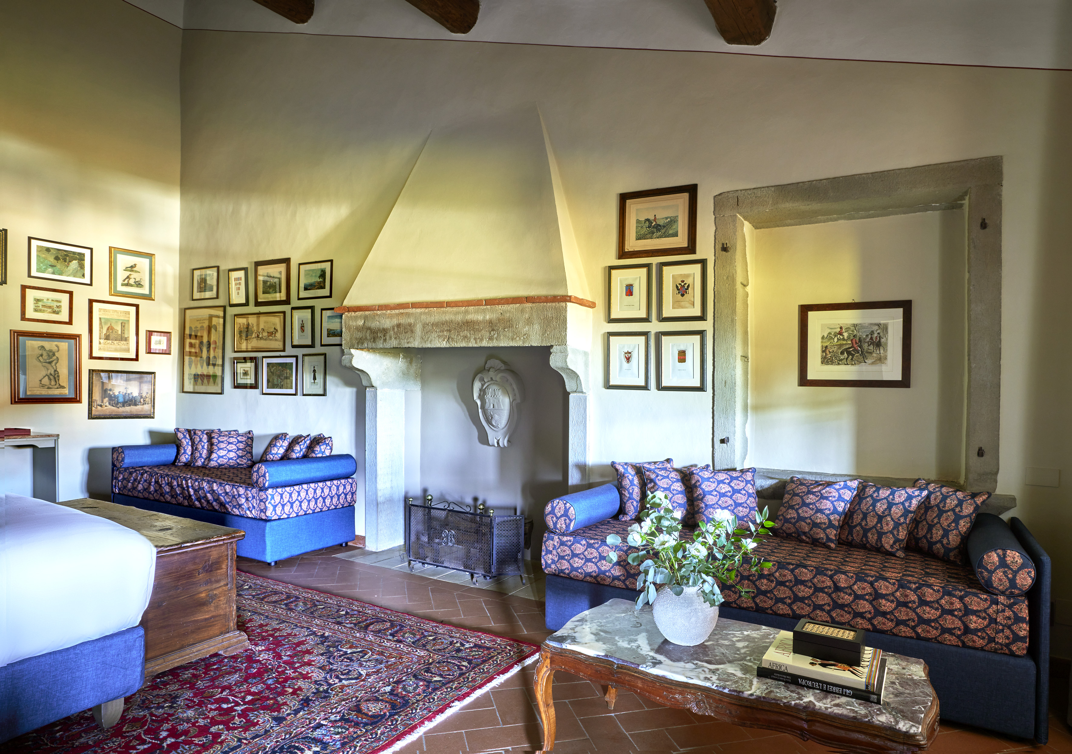 Living room with patterned daybeds, stone fireplace, and framed gallery wall.