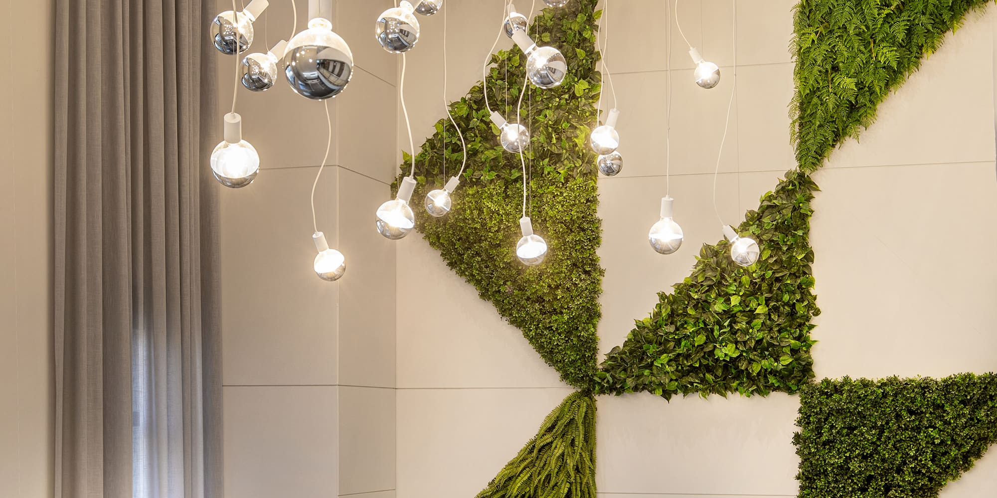 a green wall with lights from the ceiling