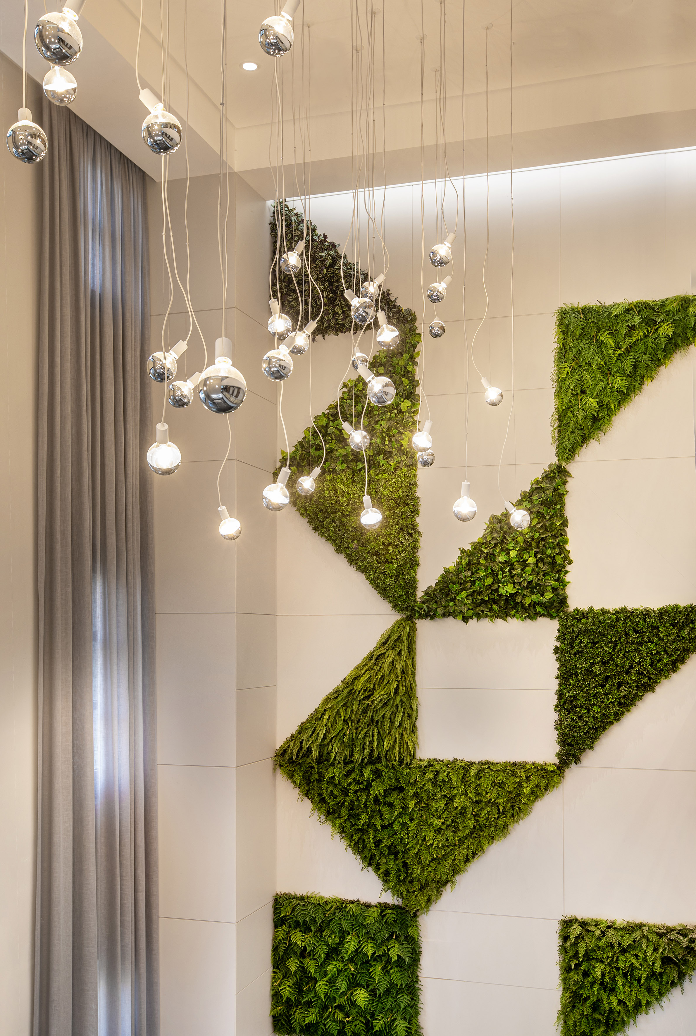 Vertical garden wall with geometric plants and modern pendant lights.