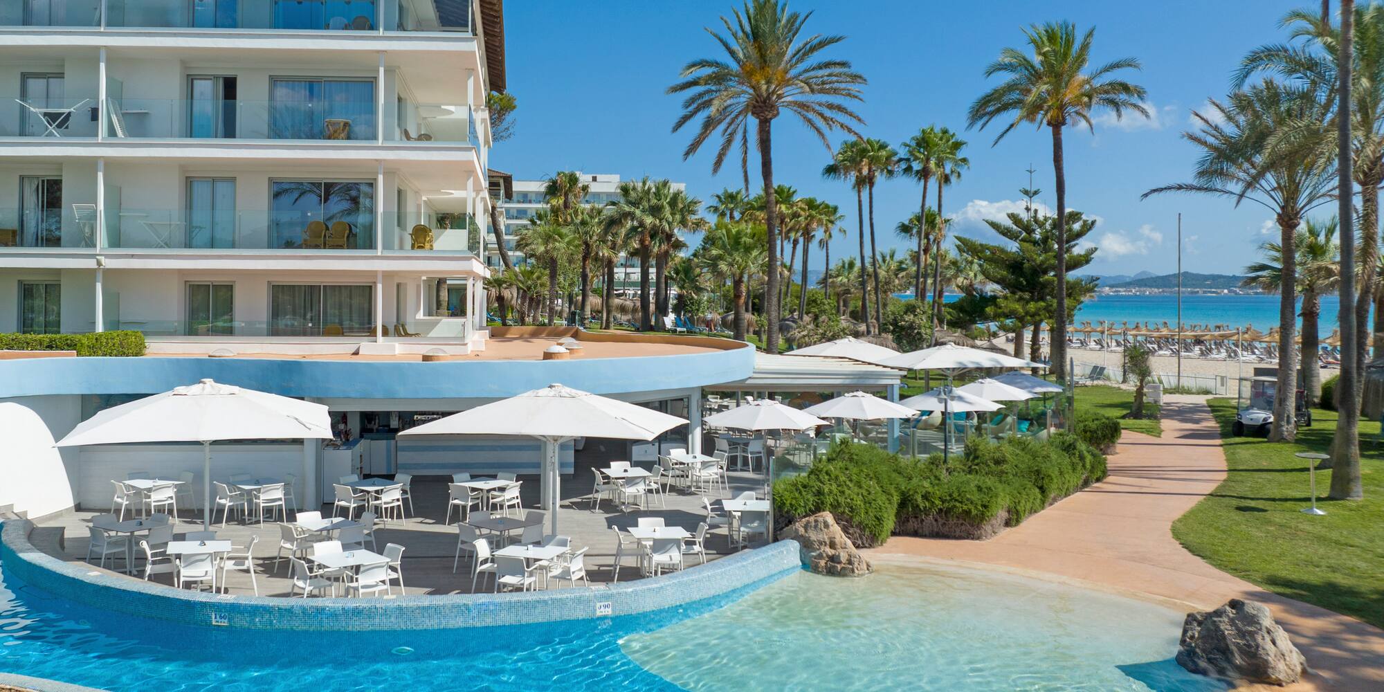 a swimming pool with tables and chairs in front of a building