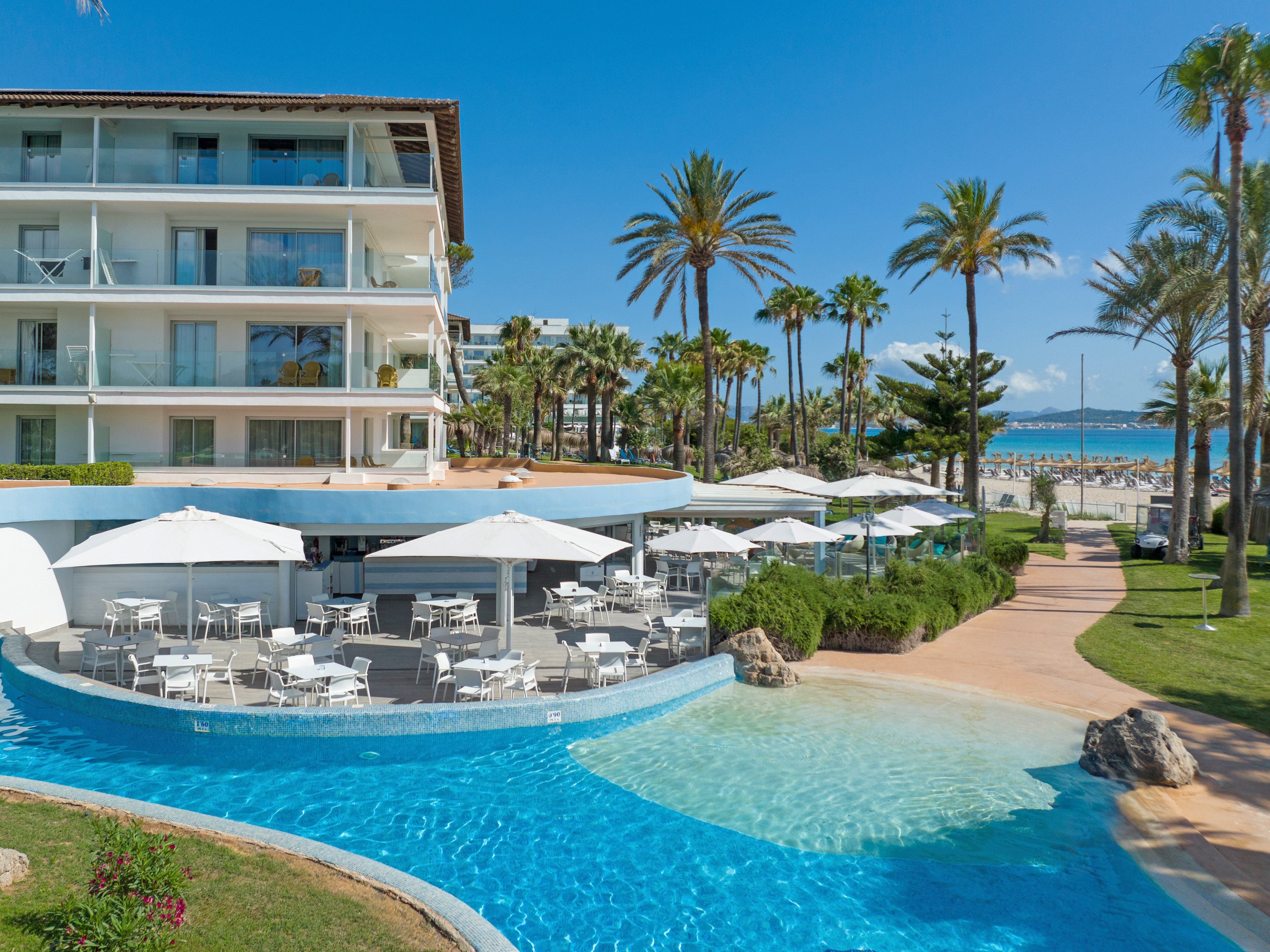 a swimming pool with tables and chairs in front of a building