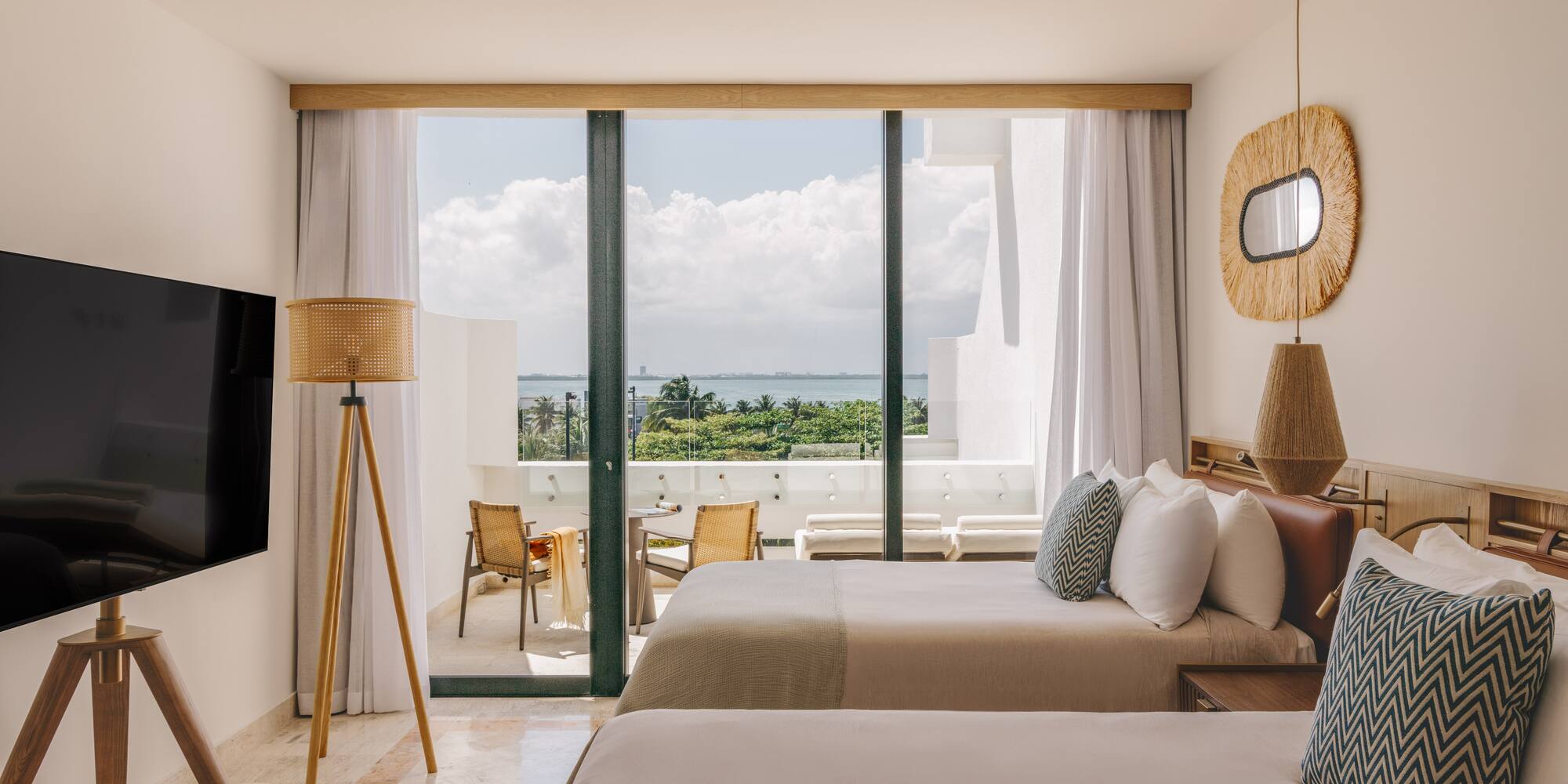 Resort hotel room, two beds, private balcony overlooking ocean and palms.