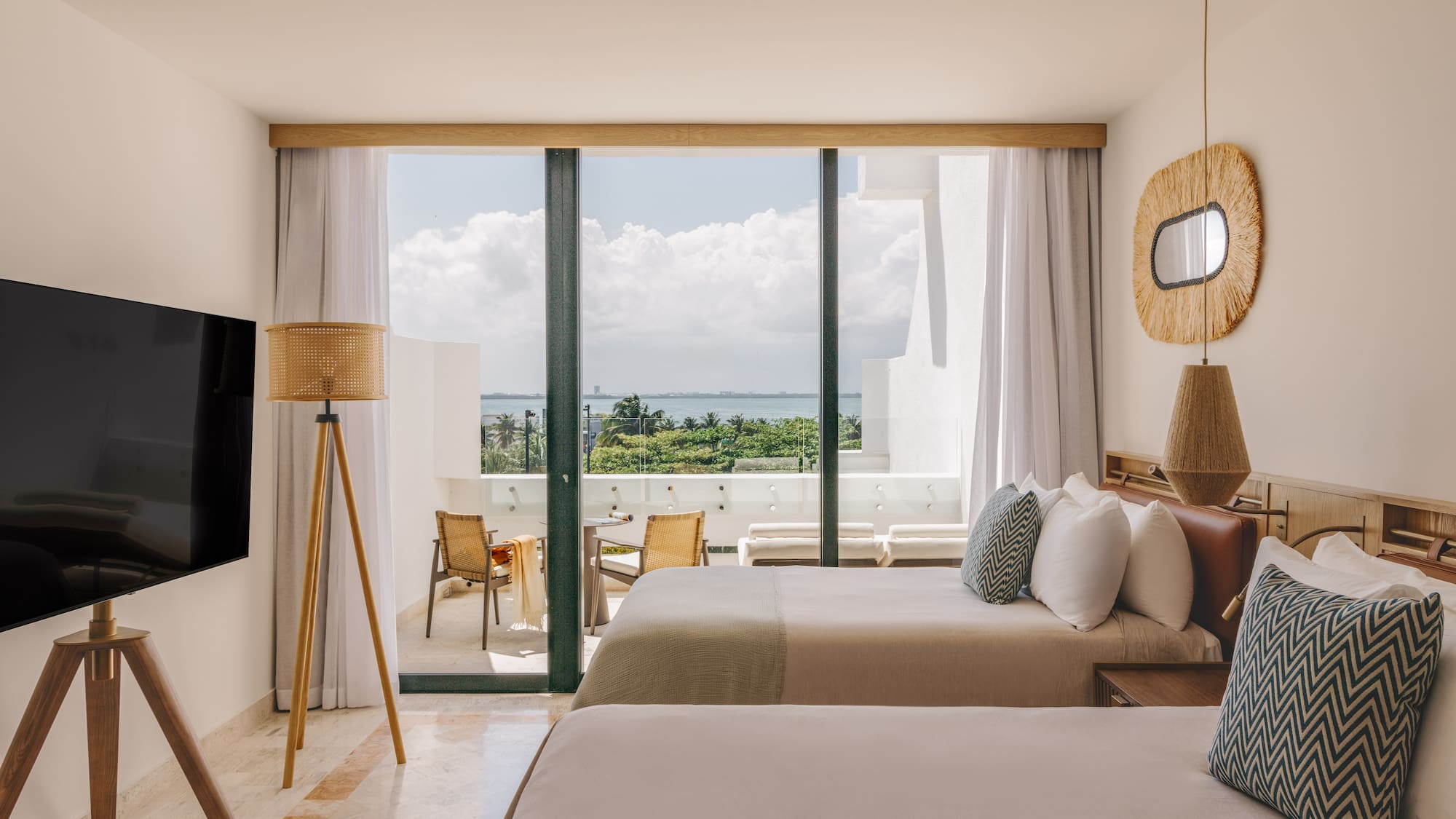 Resort hotel room, two beds, private balcony overlooking ocean and palms.