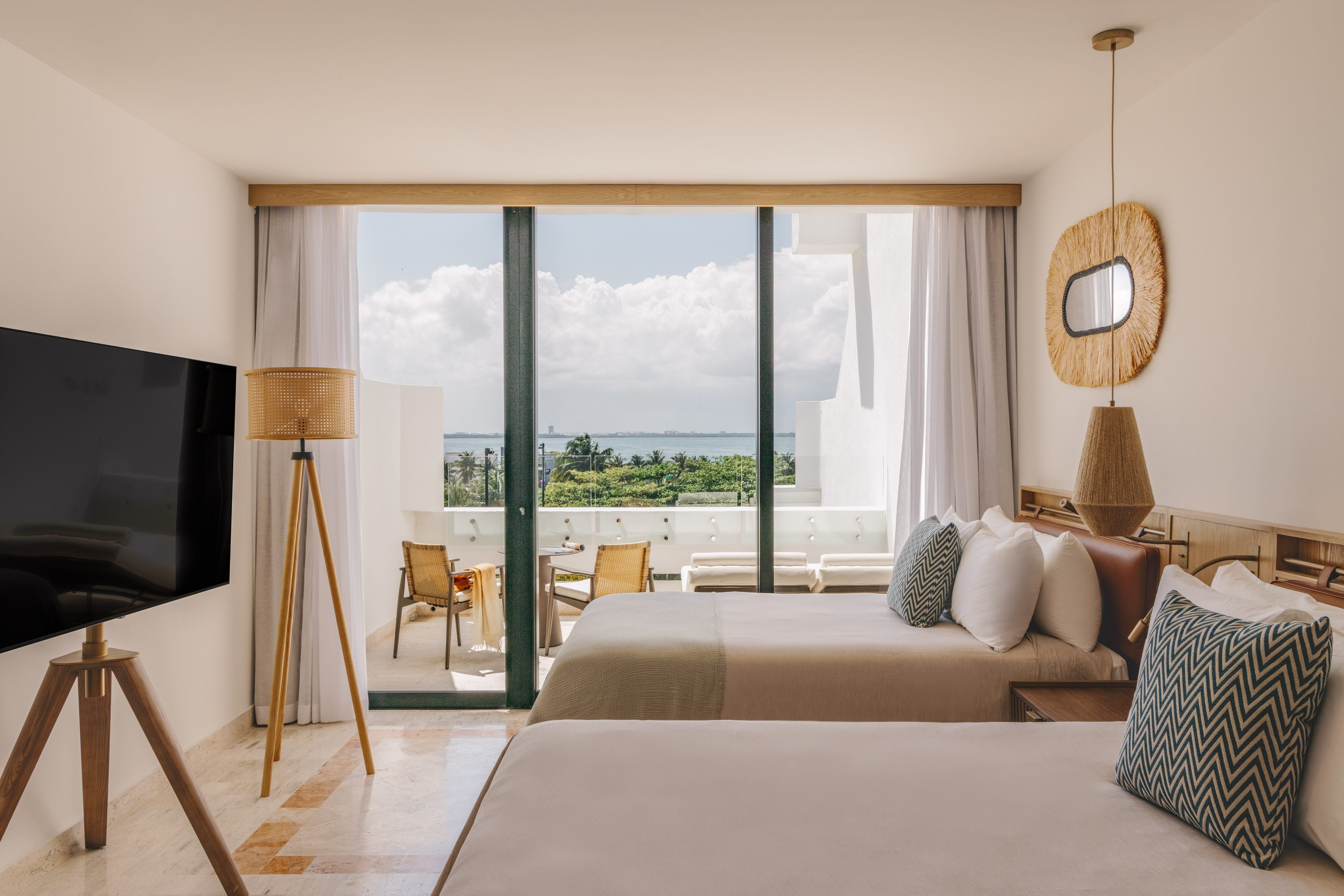 Resort hotel room, two beds, private balcony overlooking ocean and palms.